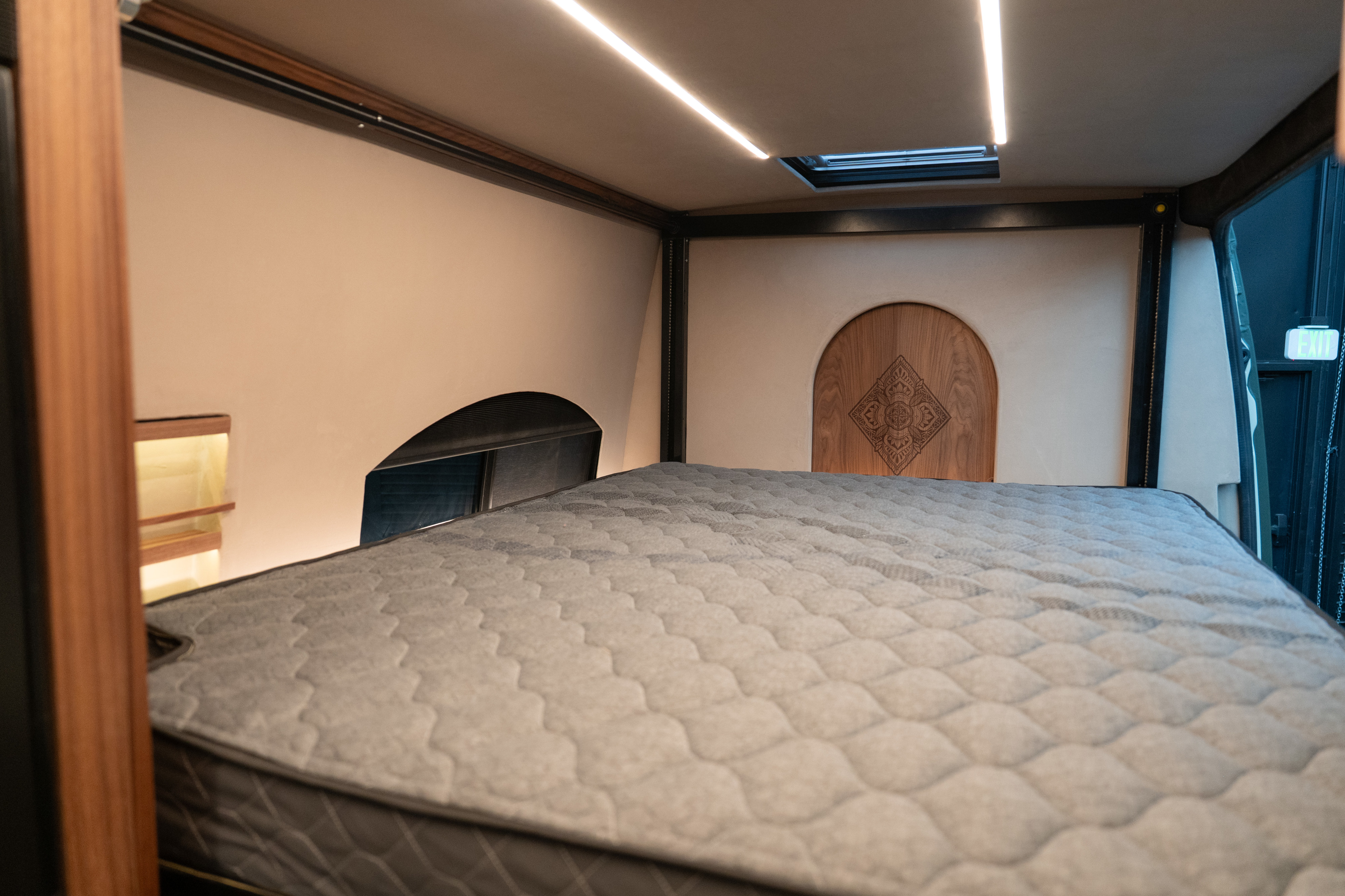 Cozy RV rental bedroom featuring a comfortable mattress, modern LED lighting, and a skylight for a restful sleep.. Other Sandy Vans 2025