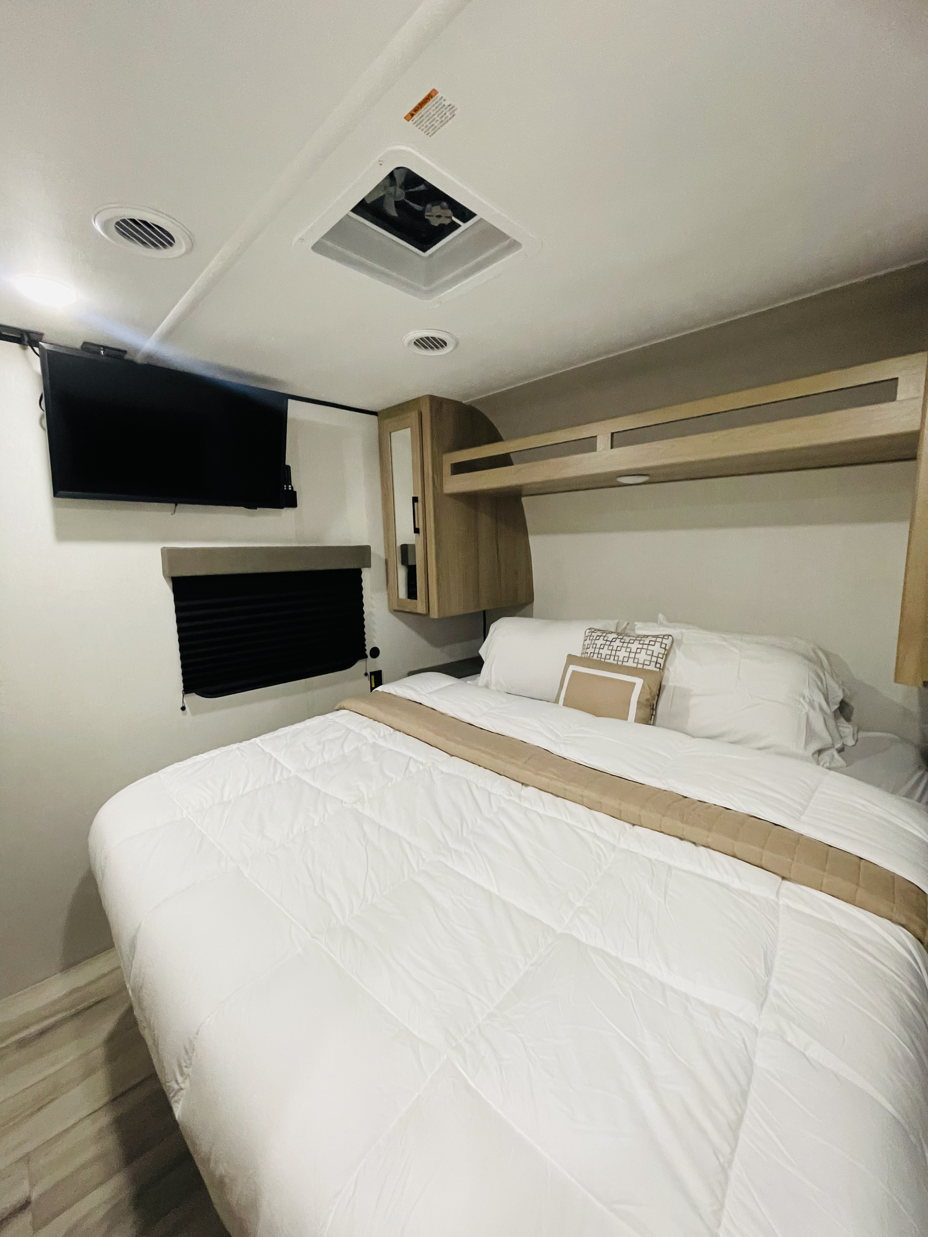 Modern RV rental bedroom with comfortable bed, wall-mounted TV, smart storage, and ceiling ventilation.. Keystone Coleman LANTERN 32BHS 2026