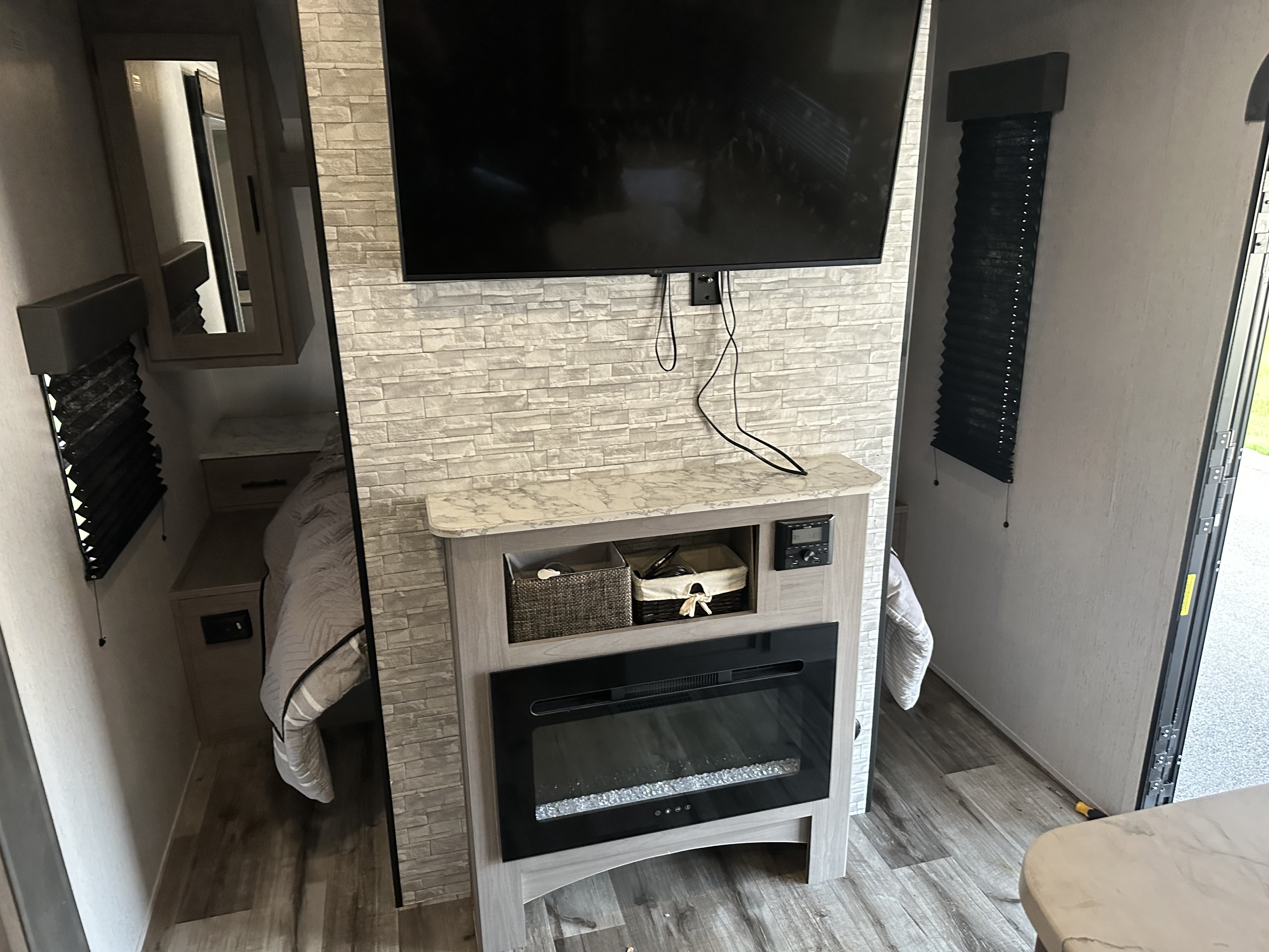 RV rental: Modern interior featuring a TV mounted above an electric fireplace, compact sleeping area, and blinds.. Dutchmen Coleman Lantern 2021