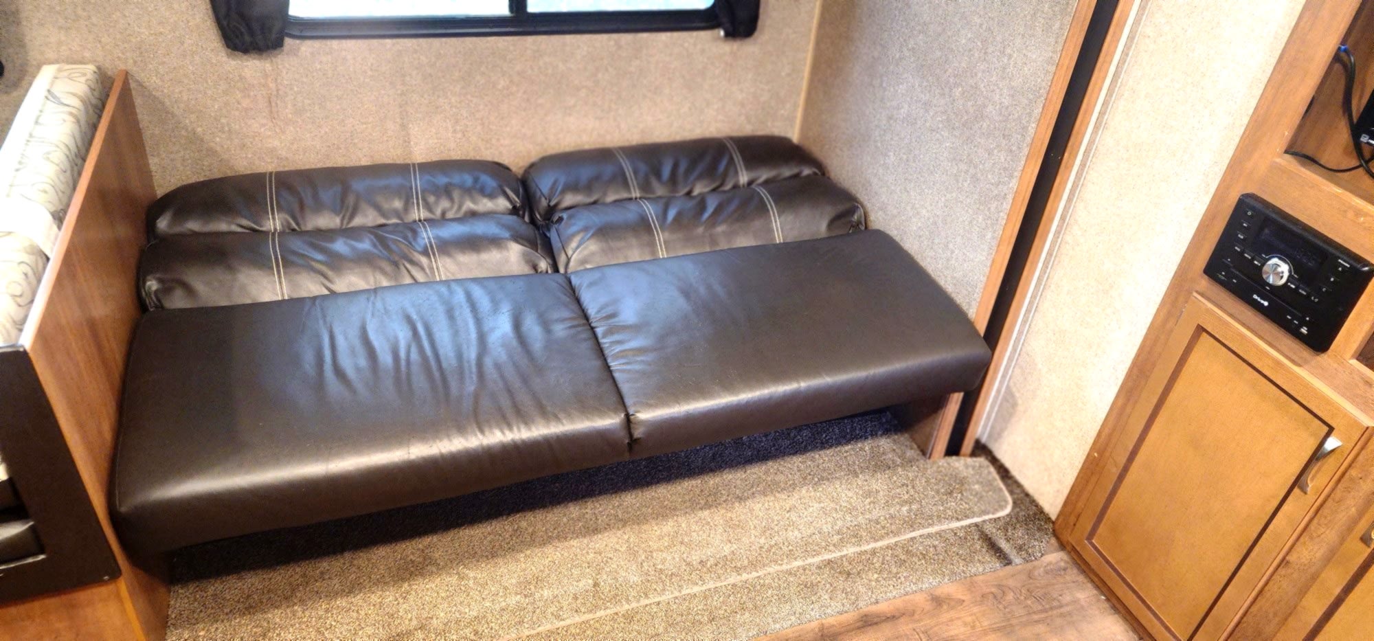 An rv rental's interior shows a dark brown convertible sofa bed, providing flexible seating & sleeping in a travel trailer.. Coachmen Coachmen Catalina SBX 261BHS 2019