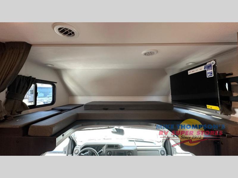 Spacious RV rental cab-over bunk features comfortable sleeping cushions, a mounted TV, and a side window.. Forest River Sunseeker LE 2025