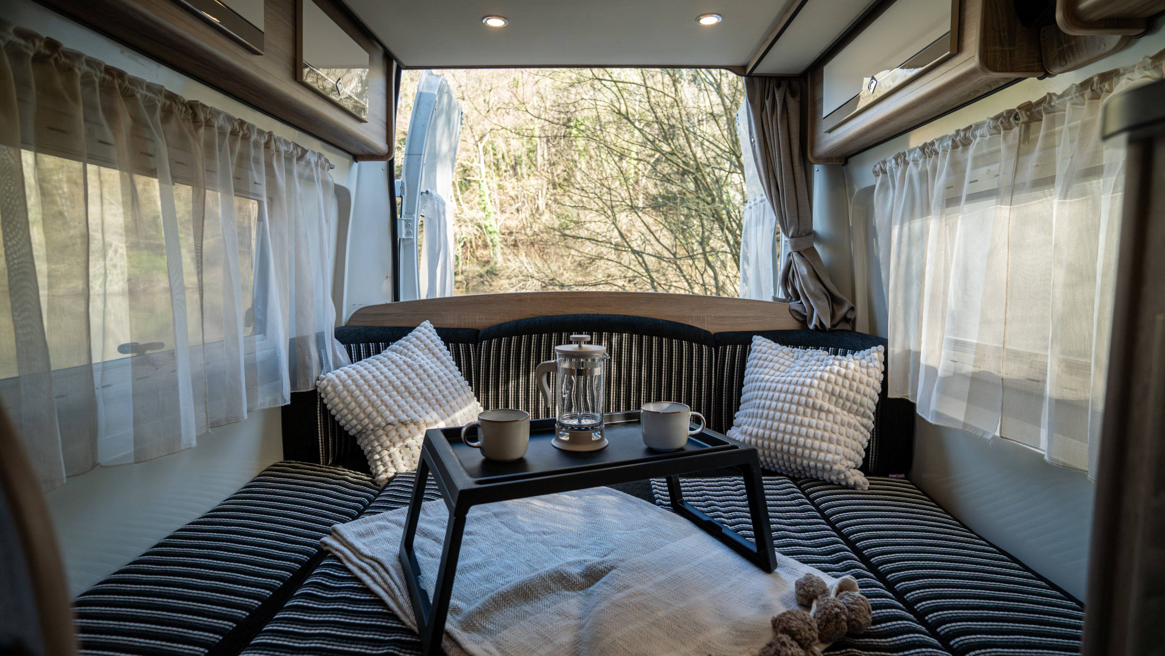 Cozy RV rental interior with a French press & coffee, offering serene nature views. Ideal for a relaxing camper getaway.. Font vendôme Plaisance D 2015