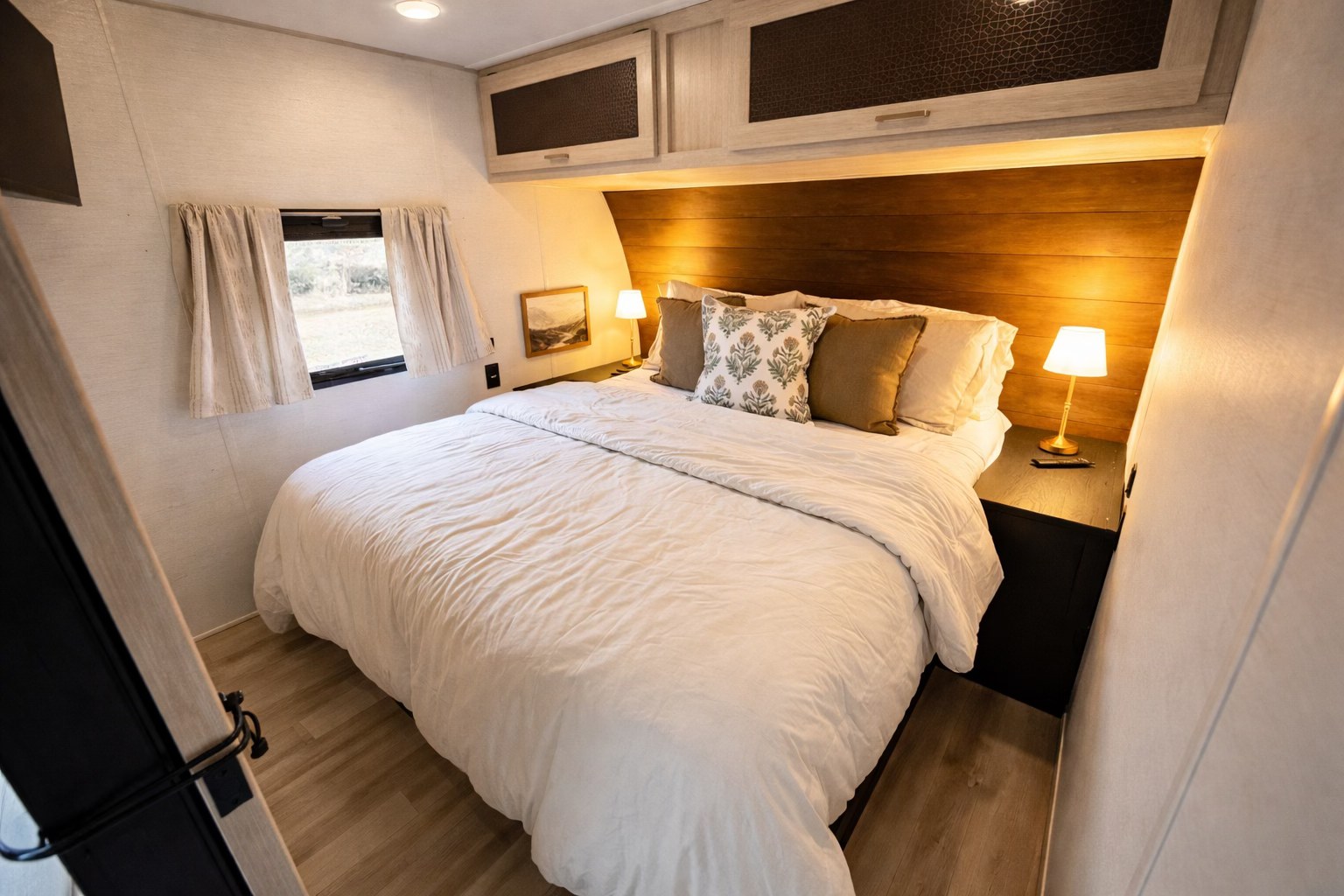 A cozy and well-appointed bedroom in an RV rental, featuring a queen bed, wooden headboard, and ambient lighting.. Avenger LT 2024