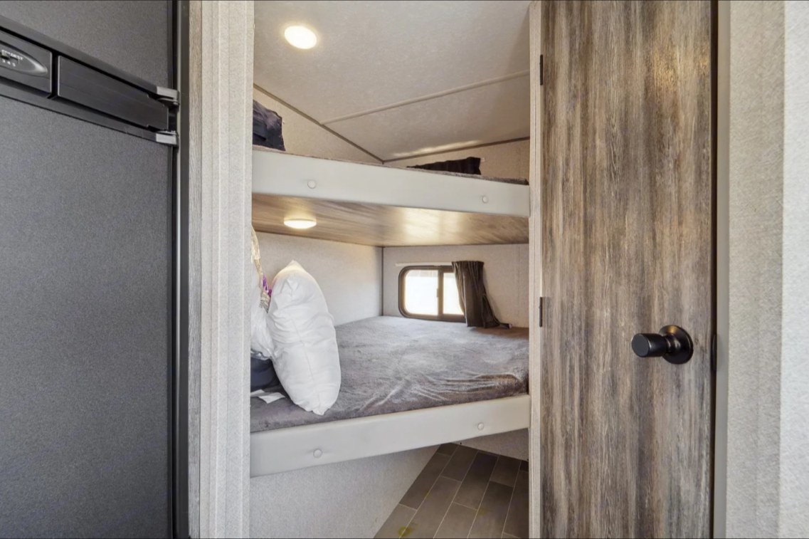This RV rental features cozy bunk beds, a window for views, and a built-in fridge, perfect for road trip adventures.. Forest River Salem FSX 2021