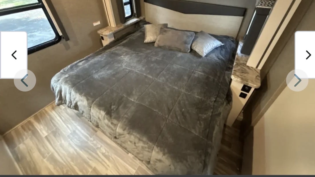 Cozy RV rental bedroom featuring a large bed with a grey comforter and pillows, along with convenient built-in bedside shelves.. Thor A.C.E. 2021
