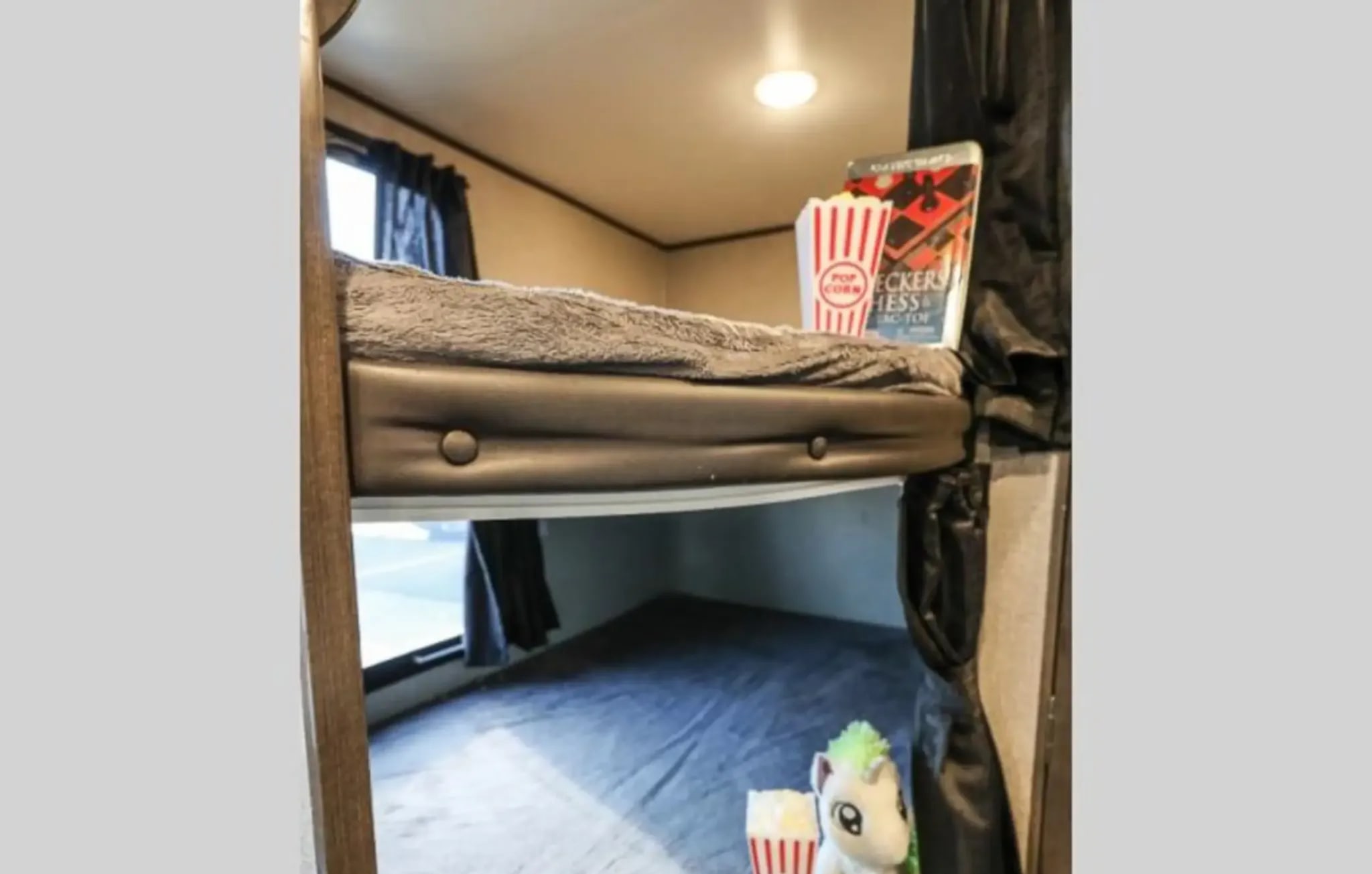 RV rental bunk beds featuring popcorn, games, and a plush unicorn toy, ready for cozy nights in a camper.. Jayco Jay Flight SLX 2021