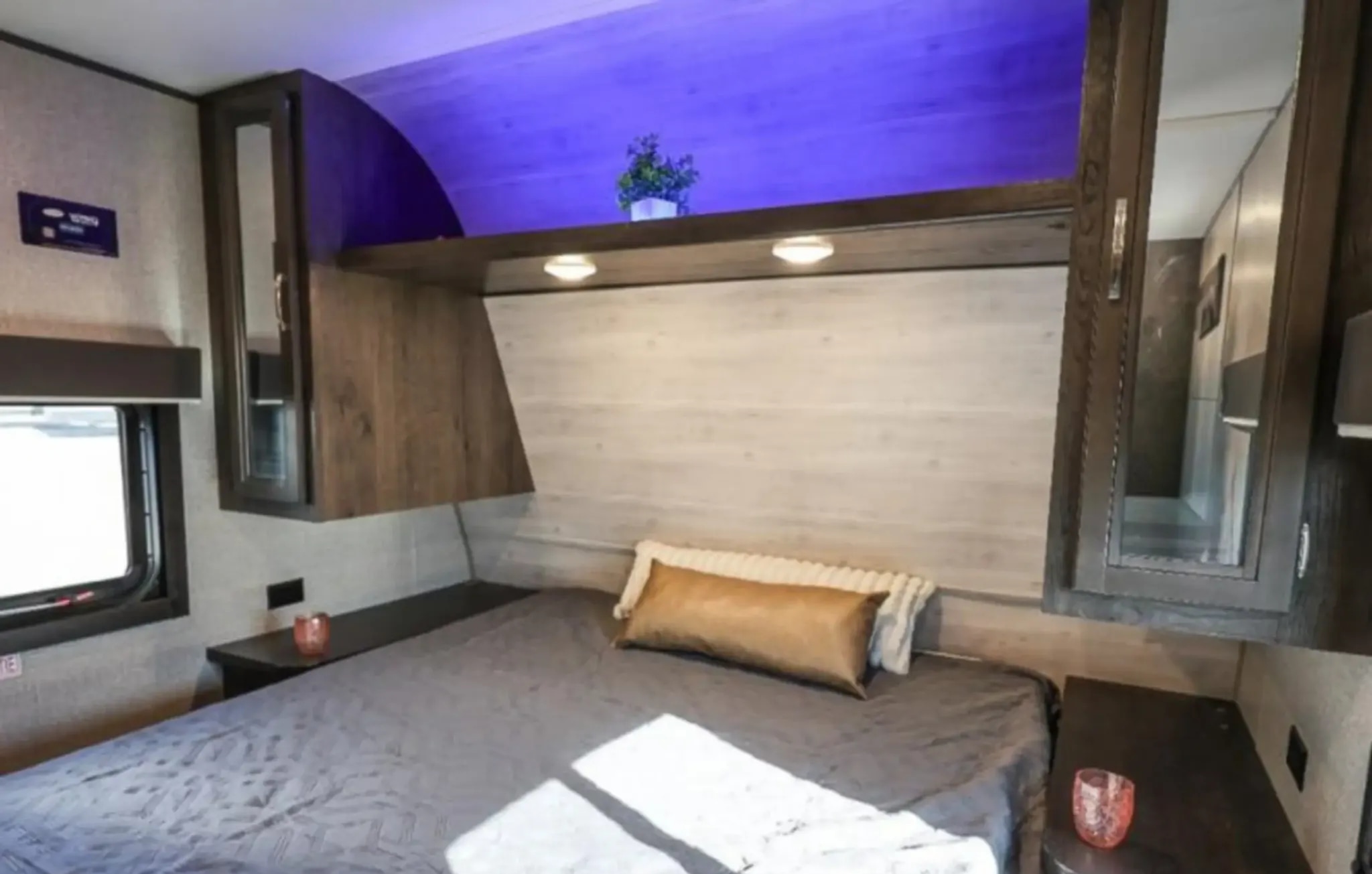 Cozy RV rental bedroom featuring a comfortable bed, overhead storage with subtle purple lighting, and practical side cabinets.. Jayco Jay Flight SLX 2021