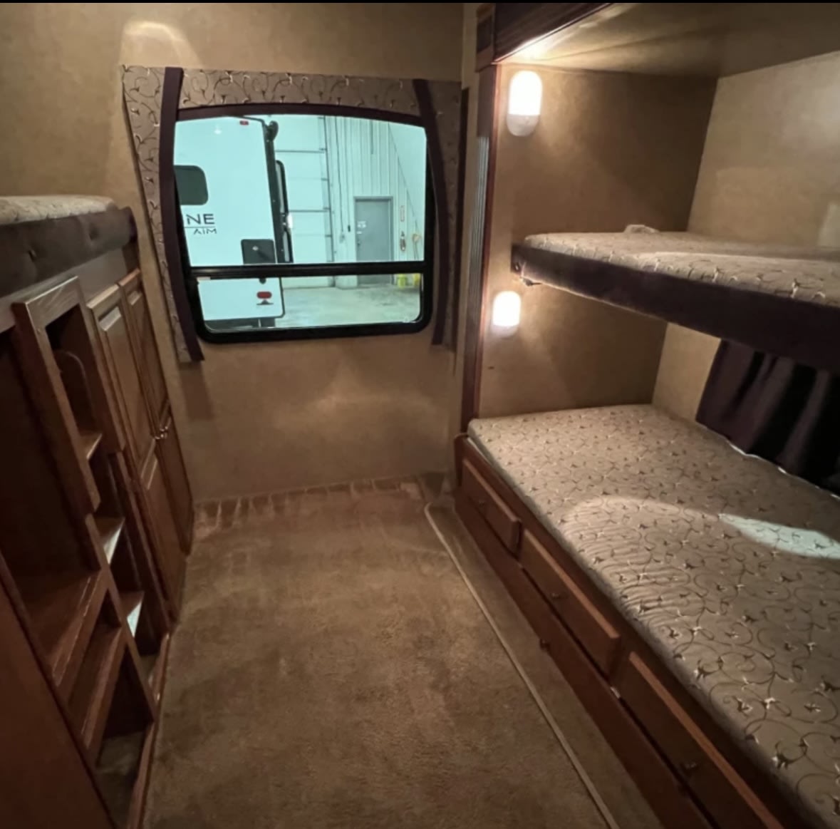 Spacious RV rental bunk room featuring twin bunk beds, under-bed storage drawers, built-in shelves, and a window.. Jayco Eagle 2020