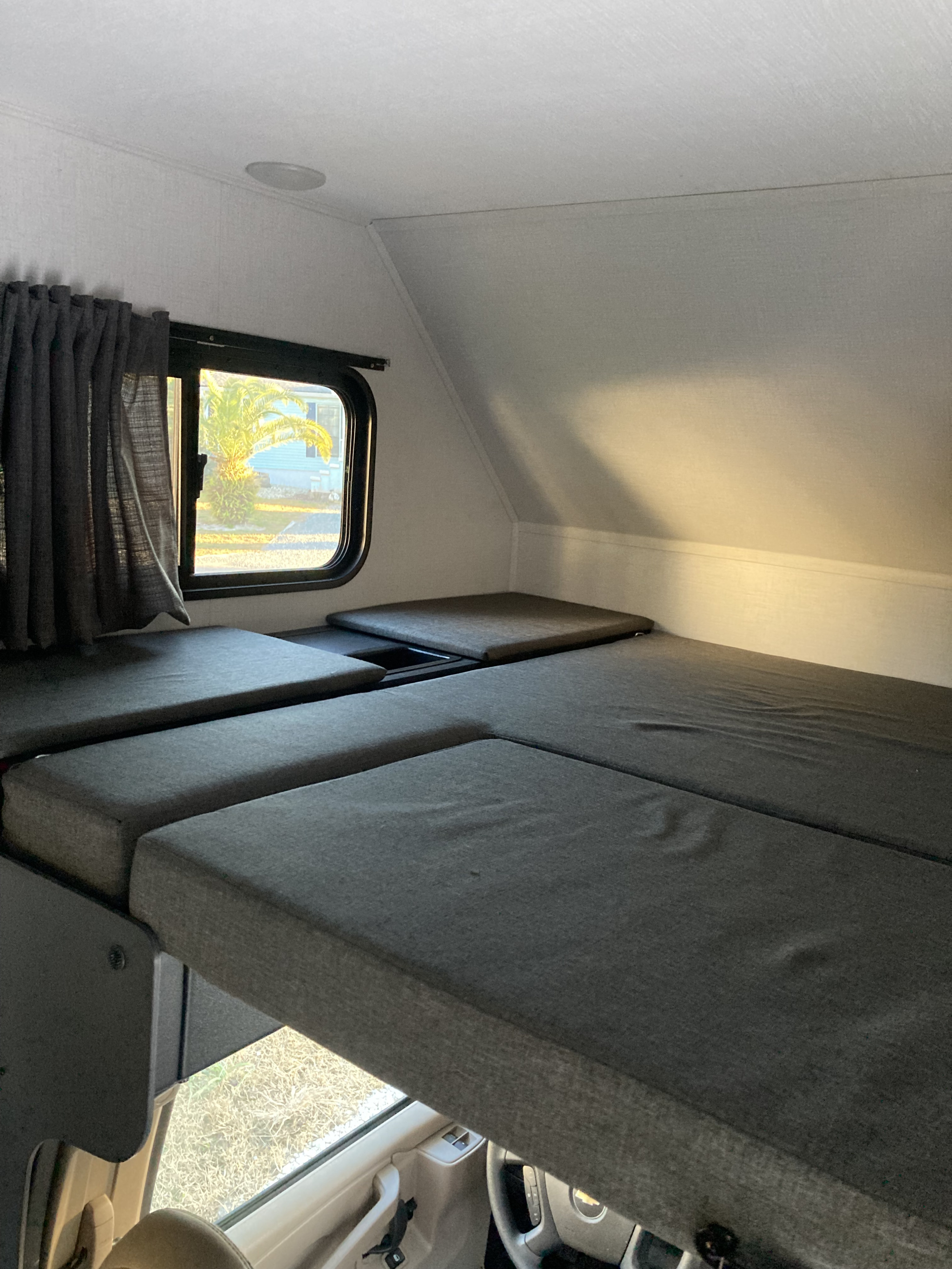 Spacious cab-over bunk sleeping area in an RV rental, offering comfortable accommodation with a view through the window.. Forester LE 2024