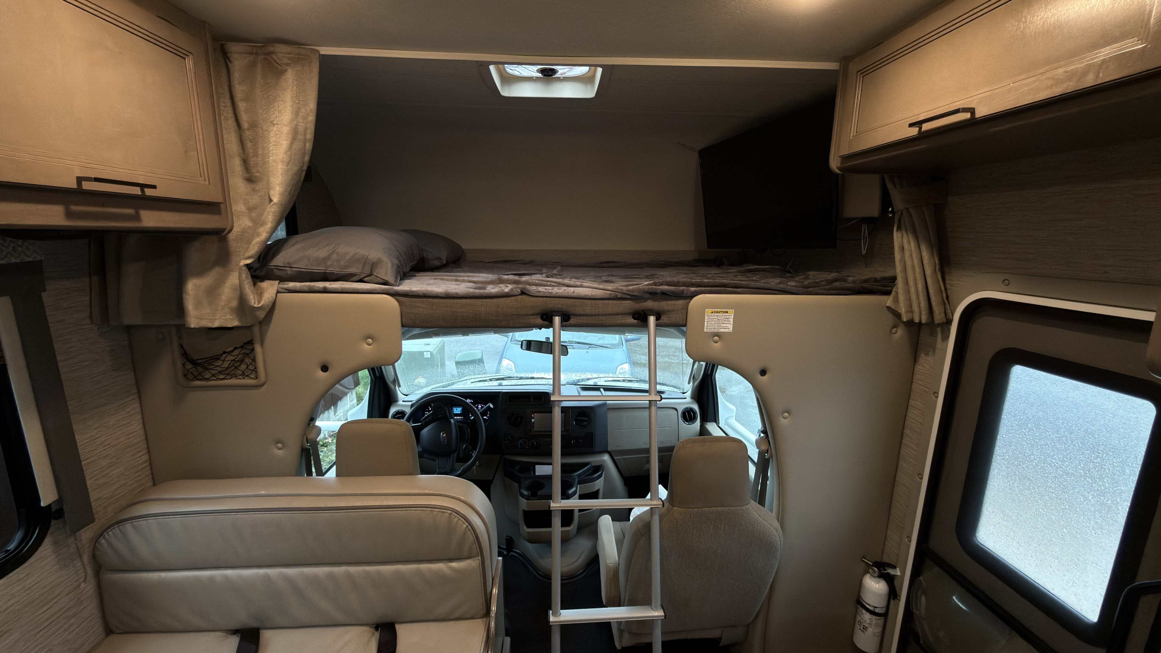 Spacious RV rental interior with a cozy cab-over bed, detailed cockpit, and seating. Ideal for road trips.. Thor Four Winds 2022