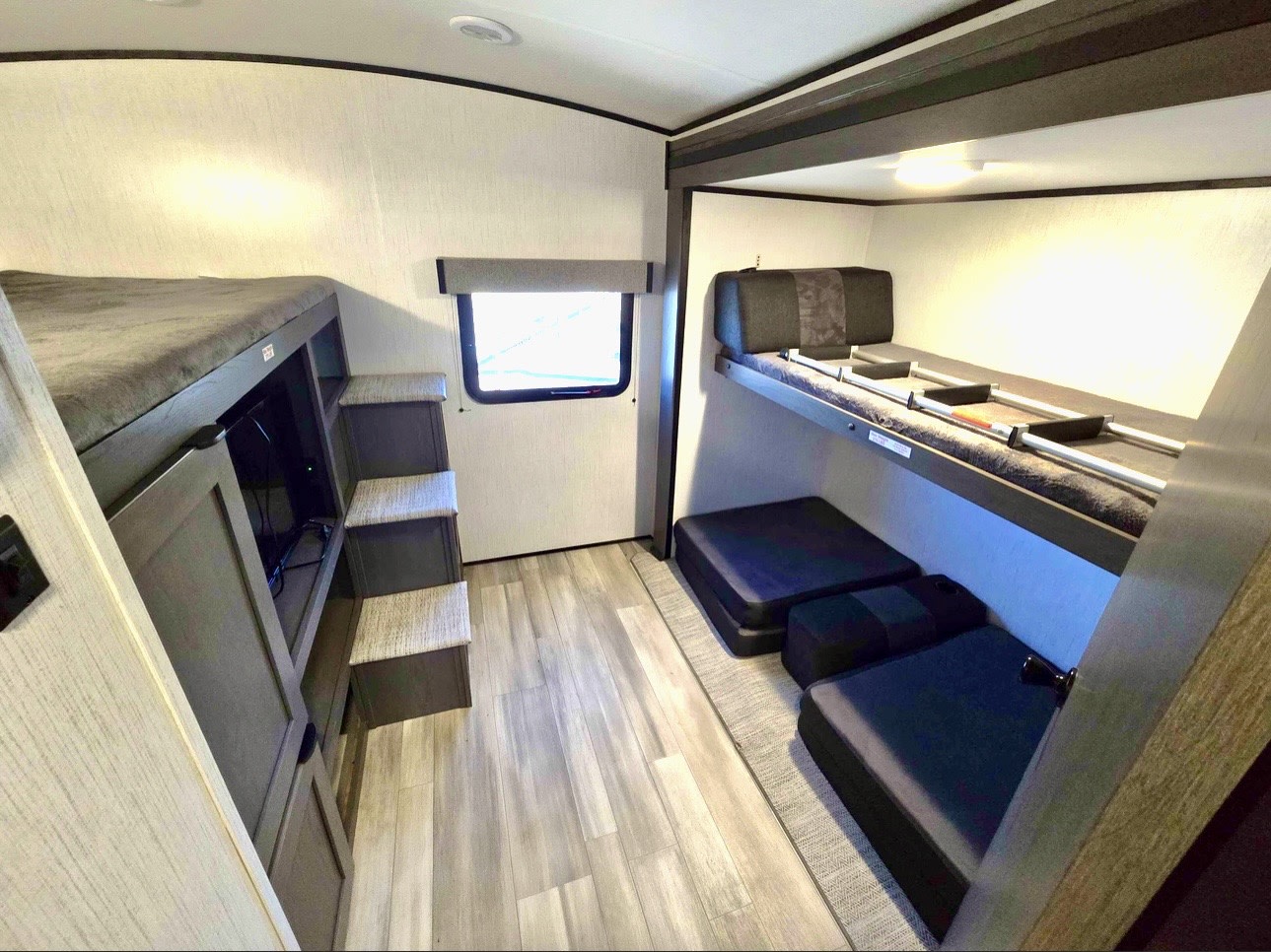 Modern RV rental interior with bunk beds on both sides, steps to an upper bed, a TV, and floor cushions for ample sleeping.. Heartland Mpg cruiser 2022