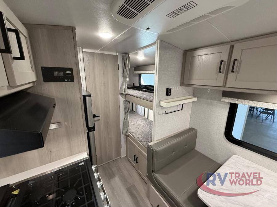 Explore this cozy RV rental interior with a compact kitchen, bunk beds, and dinette area. Ideal for family adventures.. Forest River Flagstaff E-Pro 2023