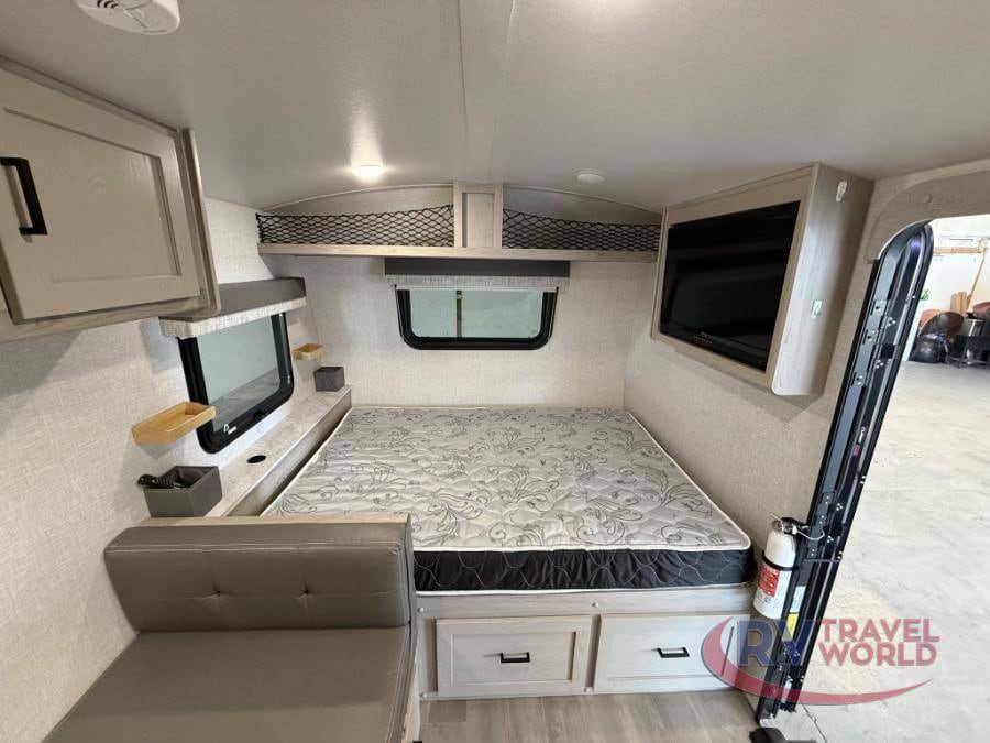 Cozy RV rental bedroom featuring a bed, sofa, TV, overhead storage, and windows. Ideal for road trips.. Forest River Flagstaff E-Pro 2023