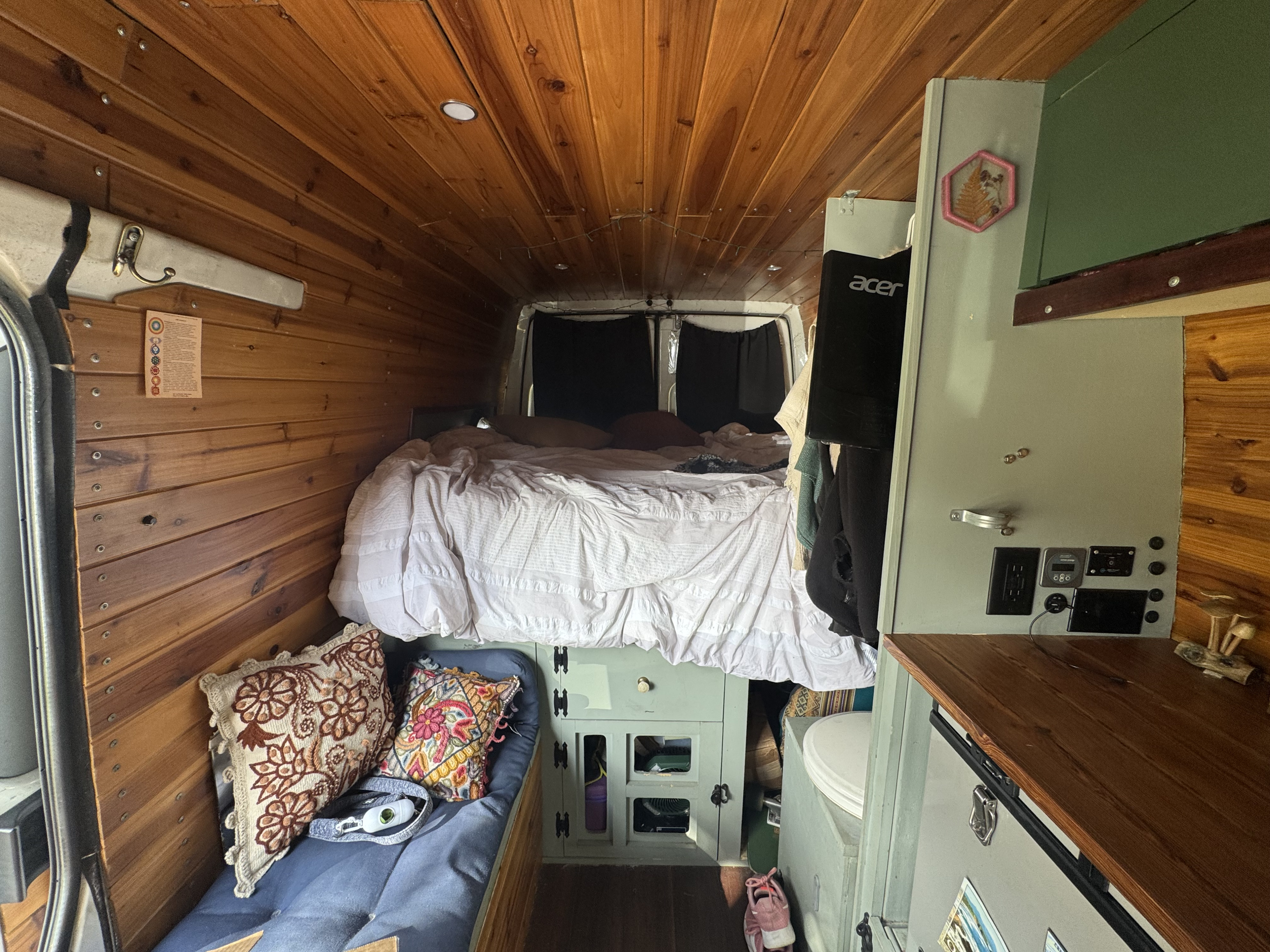Cozy custom camper van interior for your next rv rental adventure, featuring a comfy bed, wood-paneled walls, and storage.. Dodge Sprinter Van 2006