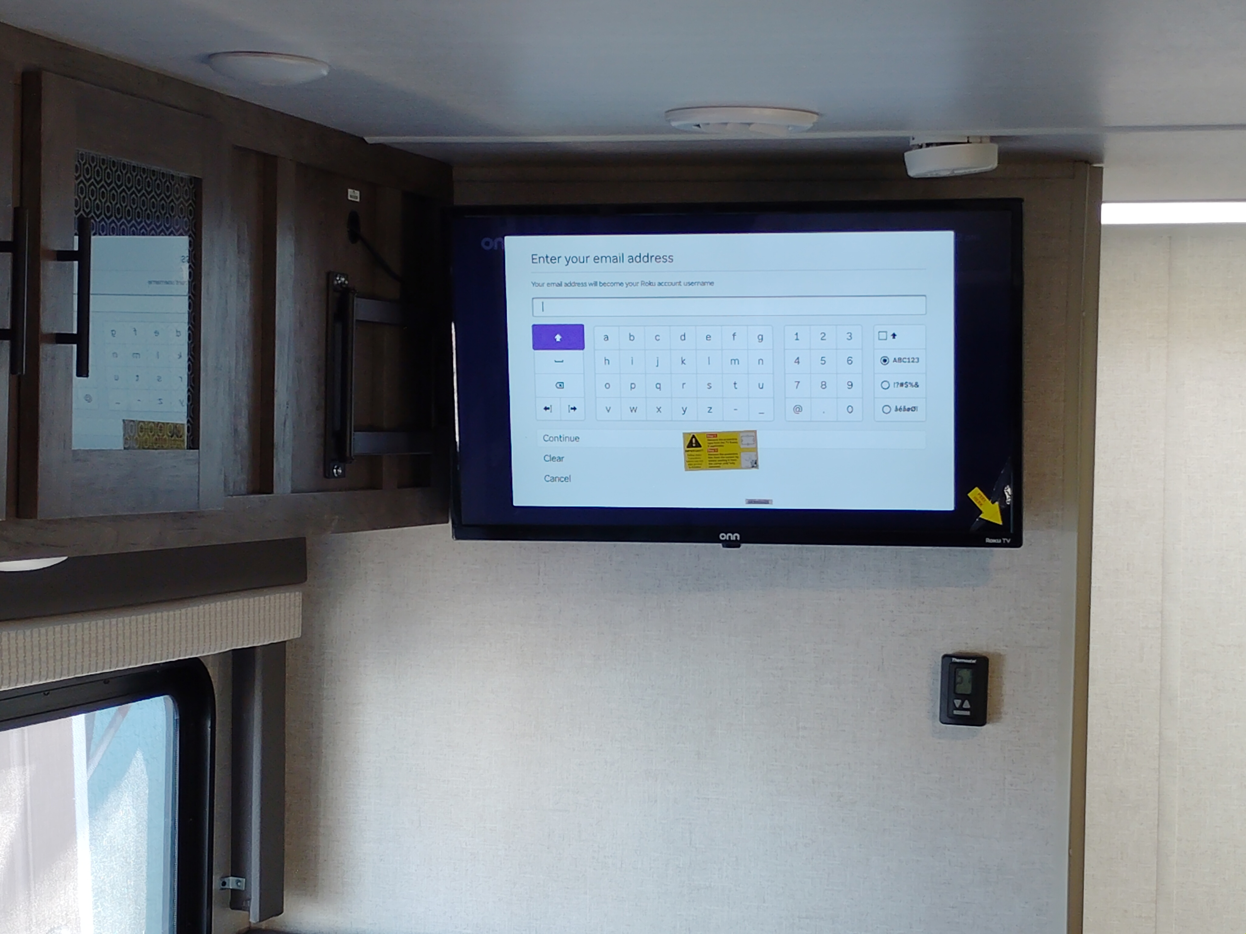 RV rental interior featuring a mounted Roku TV displaying an email login, alongside wooden cabinets, a window, and a wall thermostat.. Forest River Salem Cruise Lite 2021