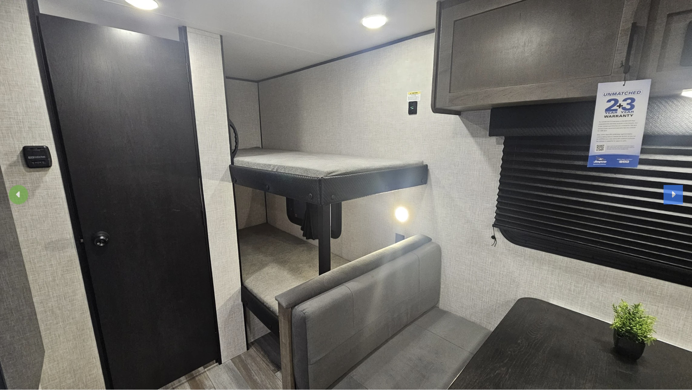 Inside this rv rental, find practical bunk beds, a cozy dining area with a plant, and storage, perfect for compact travel.. Jayco JayFlight 2026