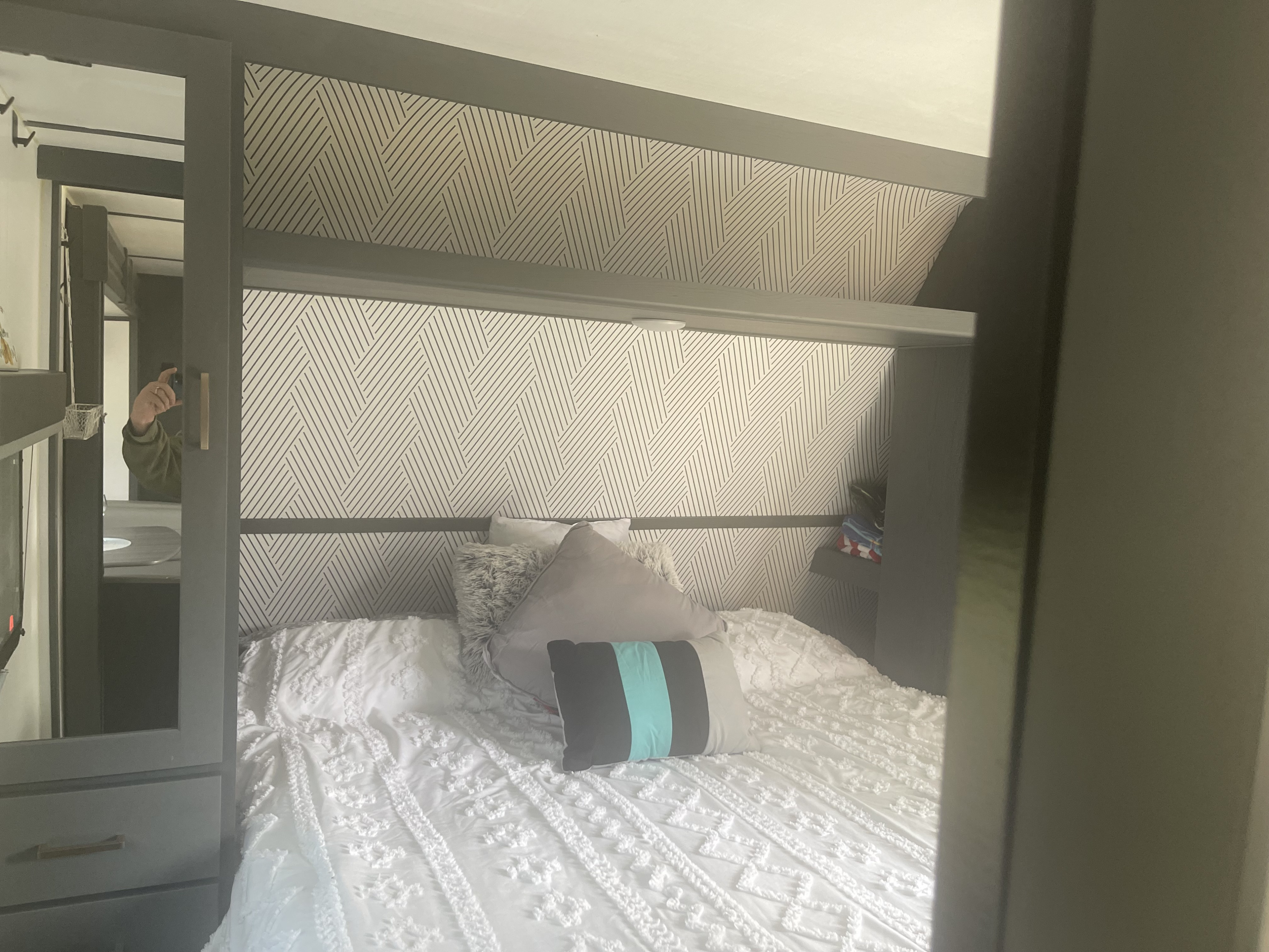 Modern RV rental bedroom featuring a geometric headboard, white bedding, and built-in storage.. Keystone RV Bullet Crossfire 2022