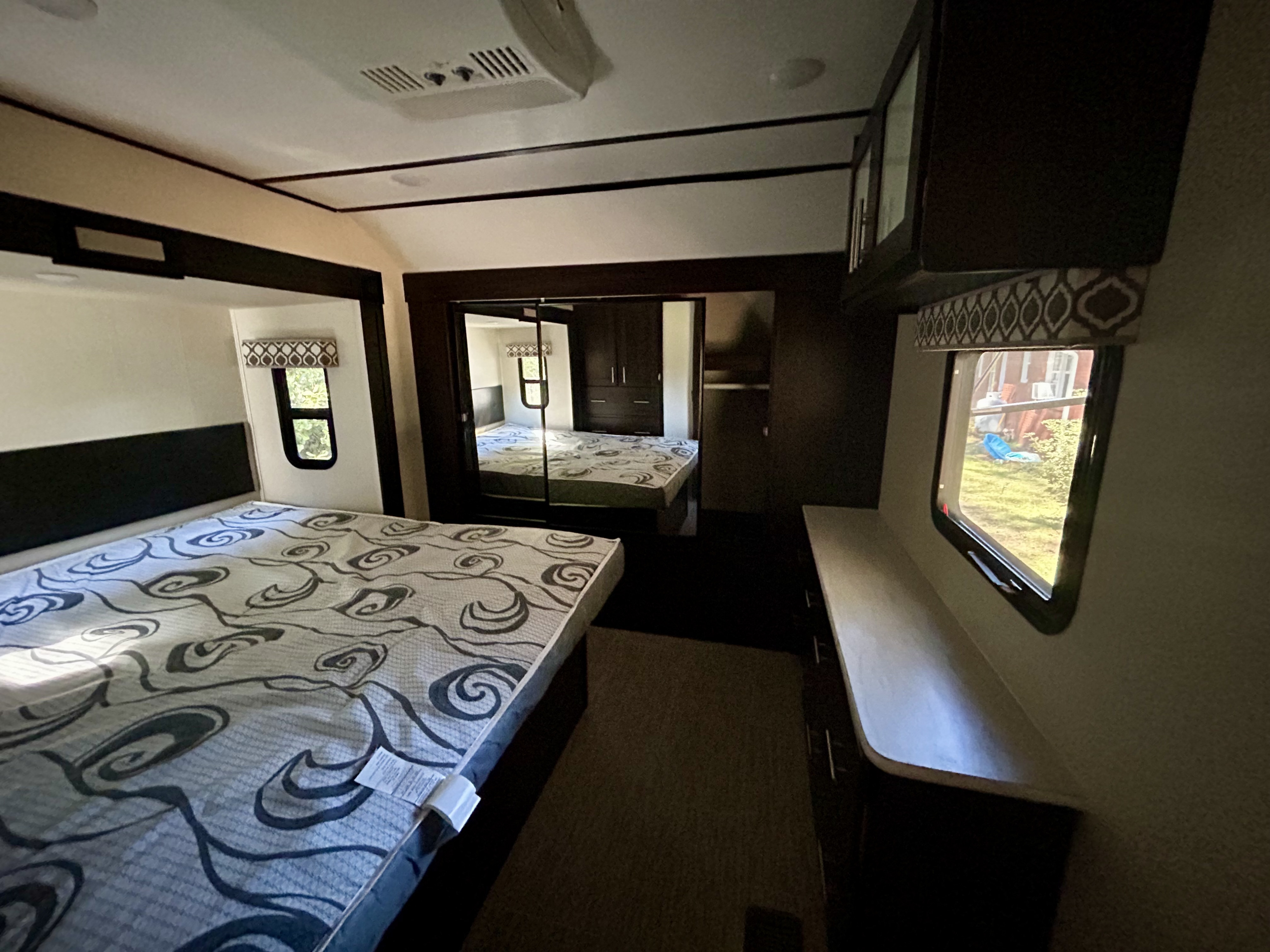Spacious RV rental bedroom with a modern interior, featuring a comfortable mattress, mirrored closet, and an AC unit for your travel comfort.. Primetime Lacrosse 2019