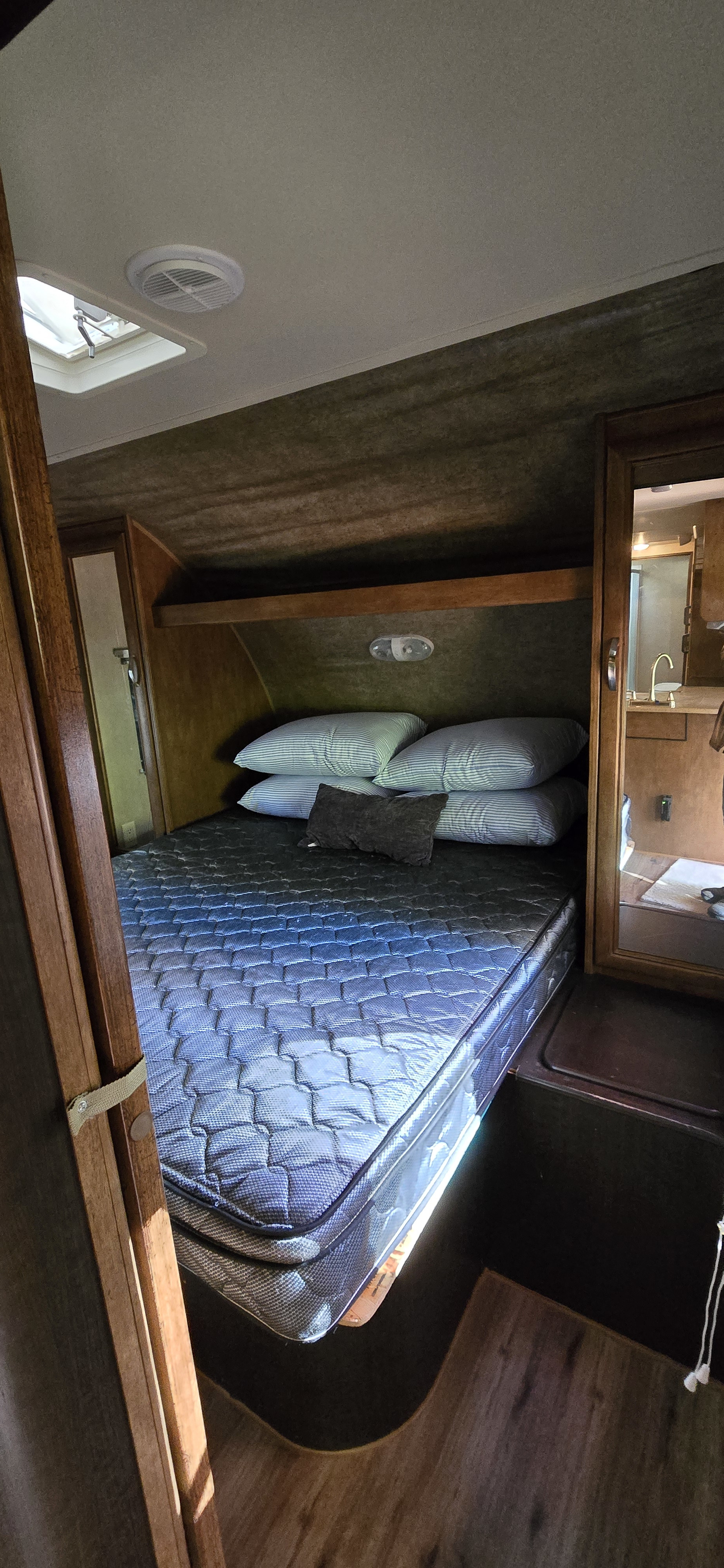 RV rental bedroom interior featuring a comfortable bed, pillows, overhead shelf, and a skylight for a cozy travel experience.. Forest River Wildwood 2016