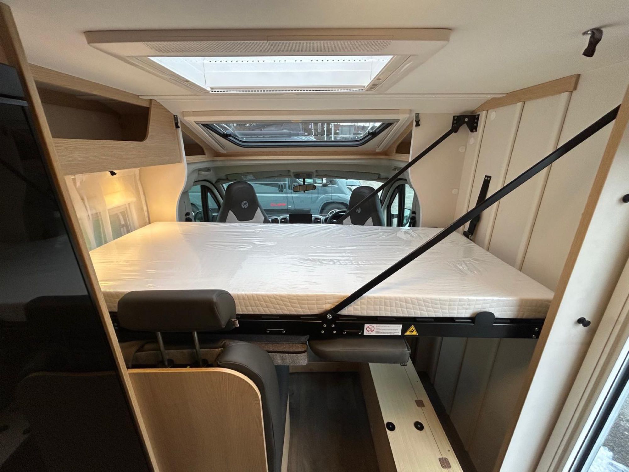 RV rental interior: A drop-down bed is lowered over the cockpit seats, with skylights illuminating the flexible space.. Sunlight V67S 2026