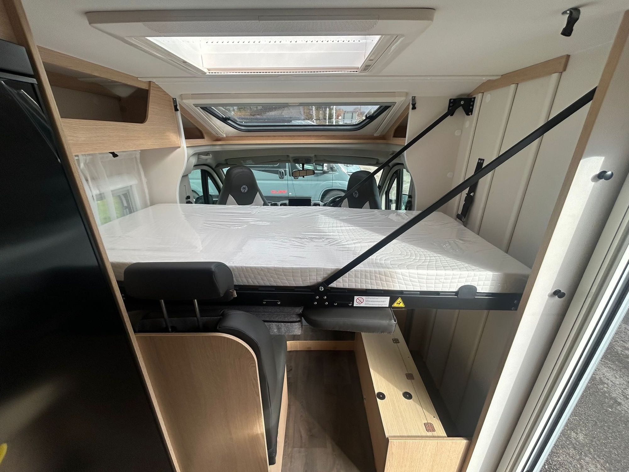 RV rental interior: A comfortable, plastic-wrapped drop-down bed is lowered, offering a cozy sleeping area in this camper.. Sunlight V67S 2026