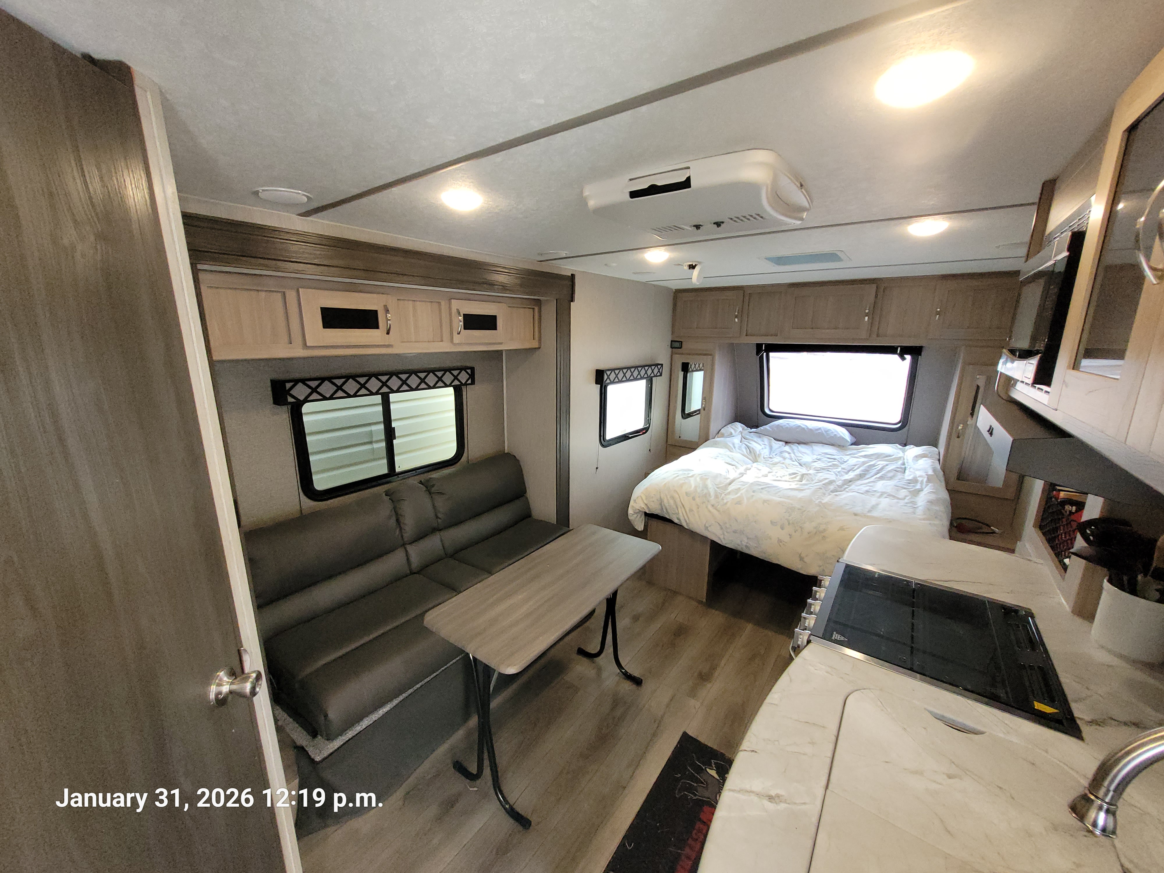 RV rental interior showing a compact kitchenette, bedroom, and dinette area with couch seating and windows.. Coachmen Freedom Express 192RBS 2021