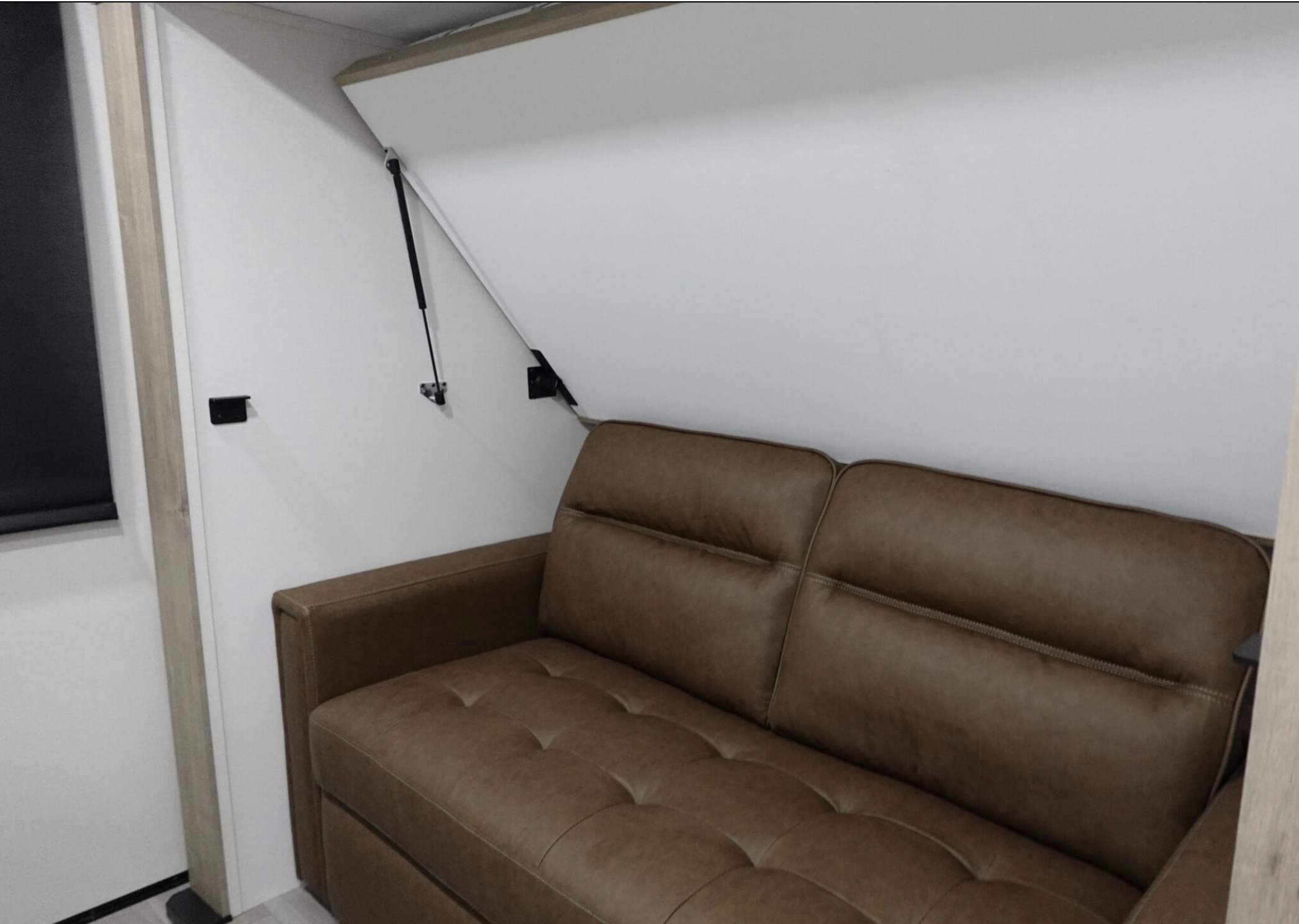 RV rental interior featuring a brown sofa with a space-saving murphy bed mechanism above, ideal for comfort.. Grand Design Imagine 2026