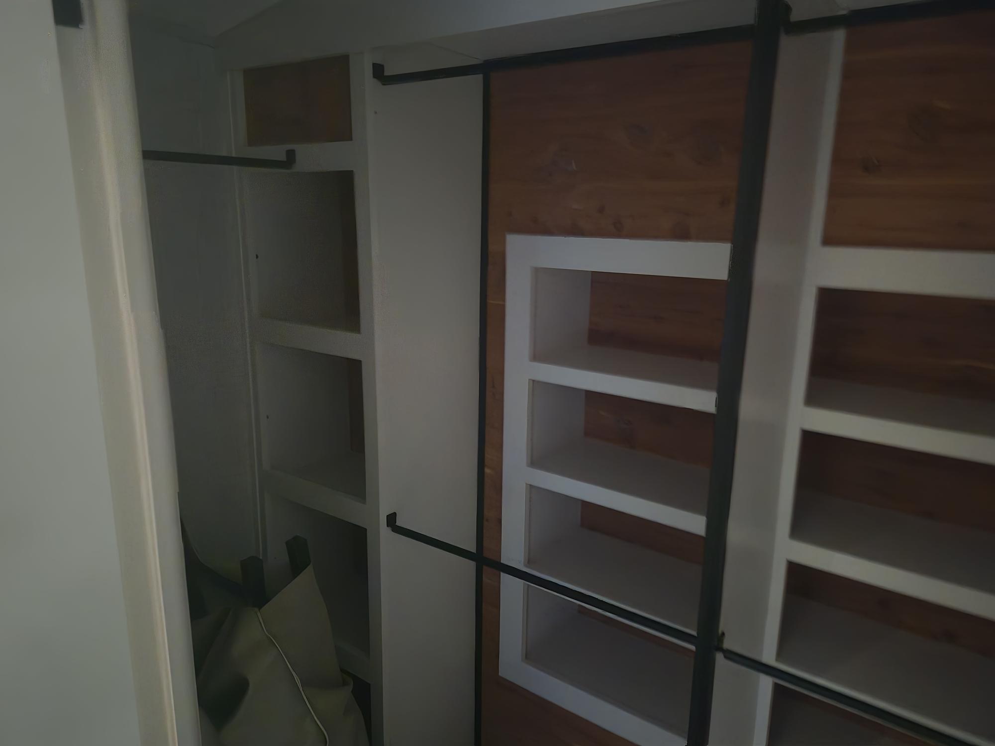 Inside an RV rental: a well-organized closet with white built-in shelves, hanging rods, and a cedar-paneled section for storage.. Jayco Pinnacle 2025