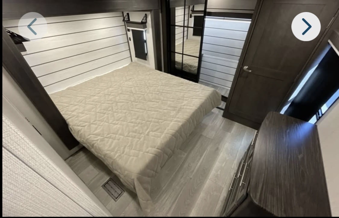 Sleek RV rental interior, showing a modern bedroom with a comfortable bed, planked walls, and dark wood details.. Keystone RV Cougar 2025