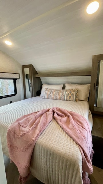 Cozy RV rental bedroom featuring a soft quilted bed, patterned pillows, a pink throw, and a window view. Ideal travel lodging.. Forest River Salem Cruise Lite 2021