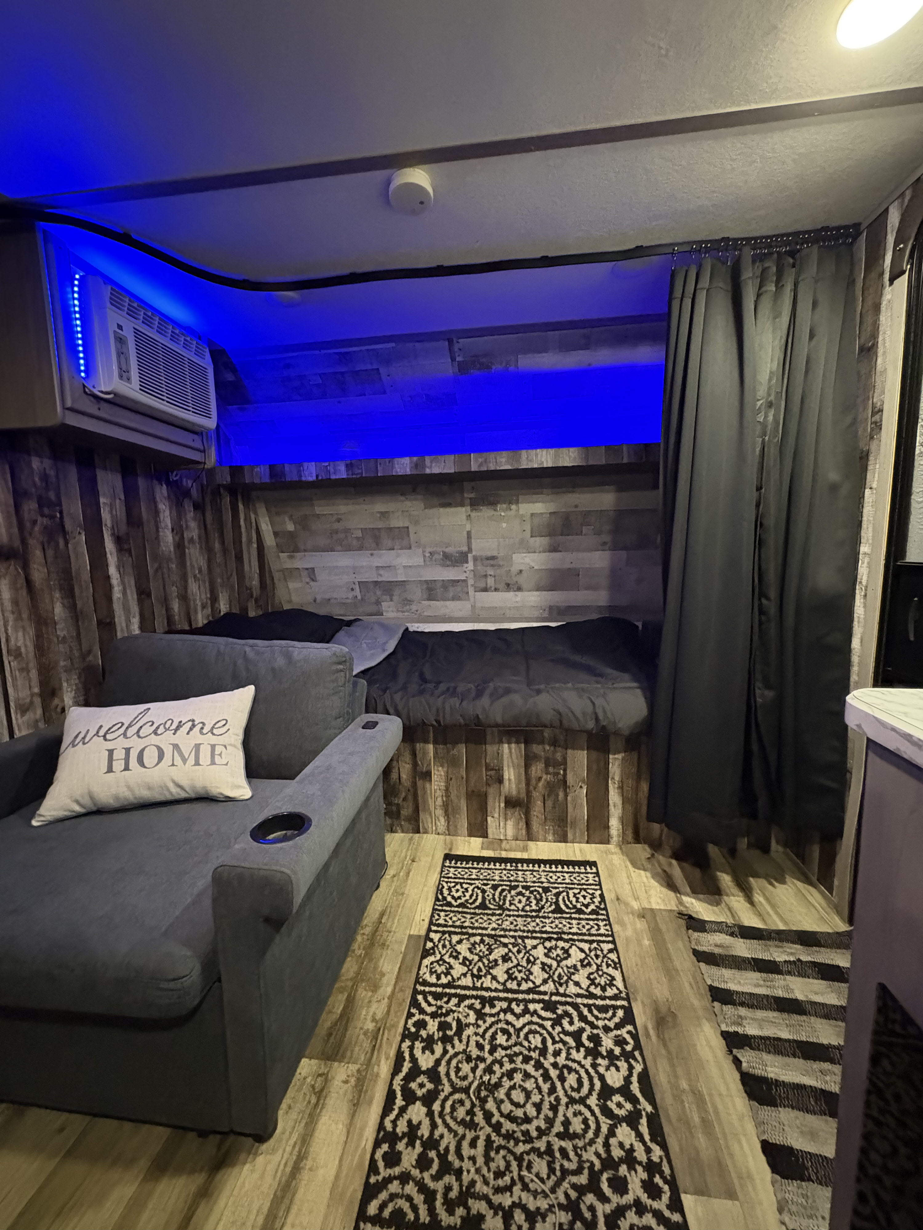 Experience comfort in this stylish rv rental. Featuring a cozy bed, seating, blue accent lights, and wood walls.. Dutchmen Coleman Lantern LT 2023
