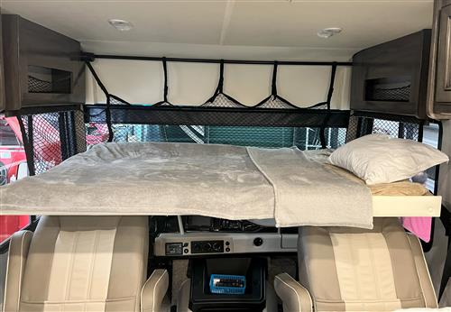 Cozy cab-over bunk bed in an RV rental, ready for adventure. Features a gray blanket, white pillow, and safety netting.. Holiday Rambler Admiral 2021