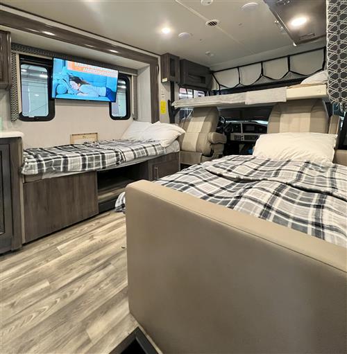 Cozy rv rental interior featuring two twin beds, an overhead bunk, and a wall-mounted TV. Ideal for family adventures.. Holiday Rambler Admiral 2021
