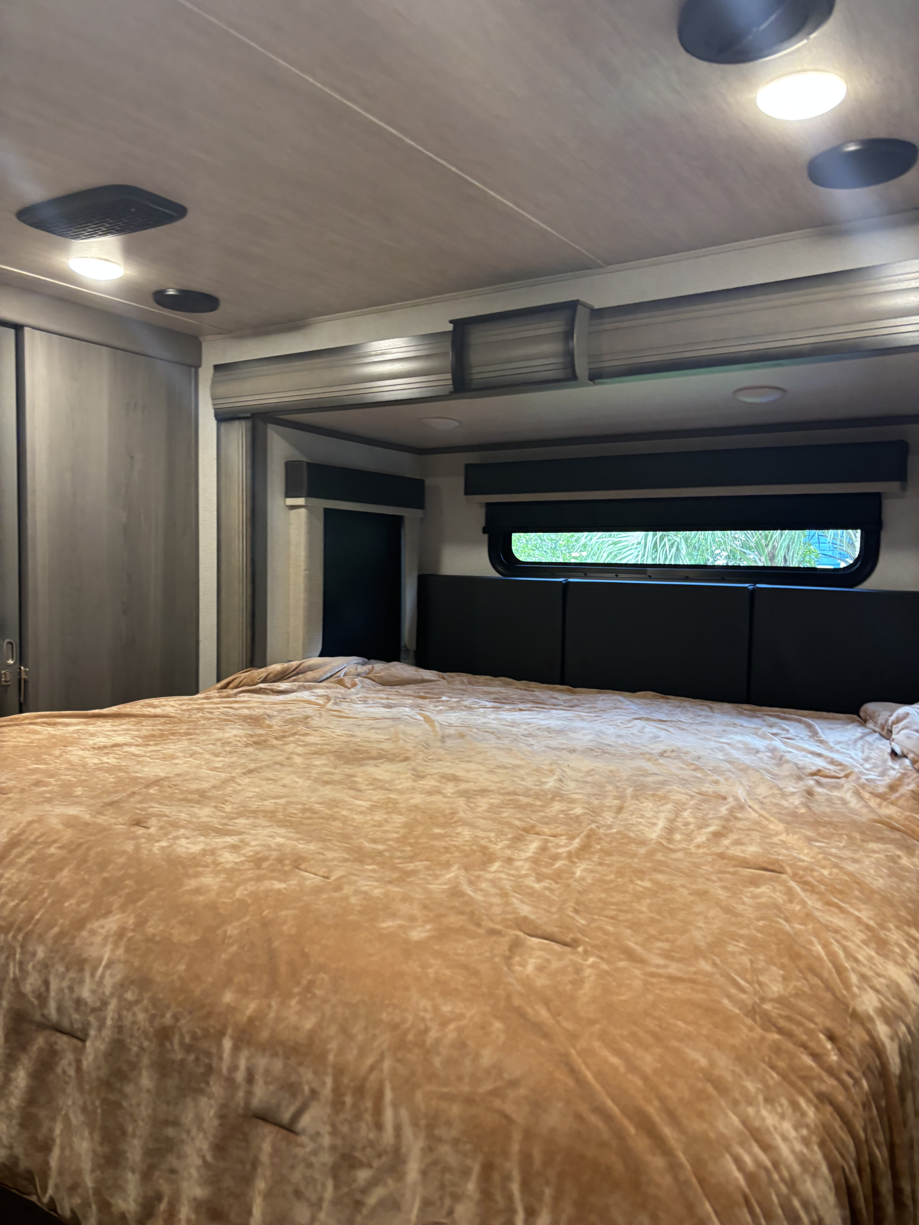 Cozy RV rental bedroom featuring a large bed with a plush comforter, modern headboard, and built-in lighting.. Keystone RV Montana 2021