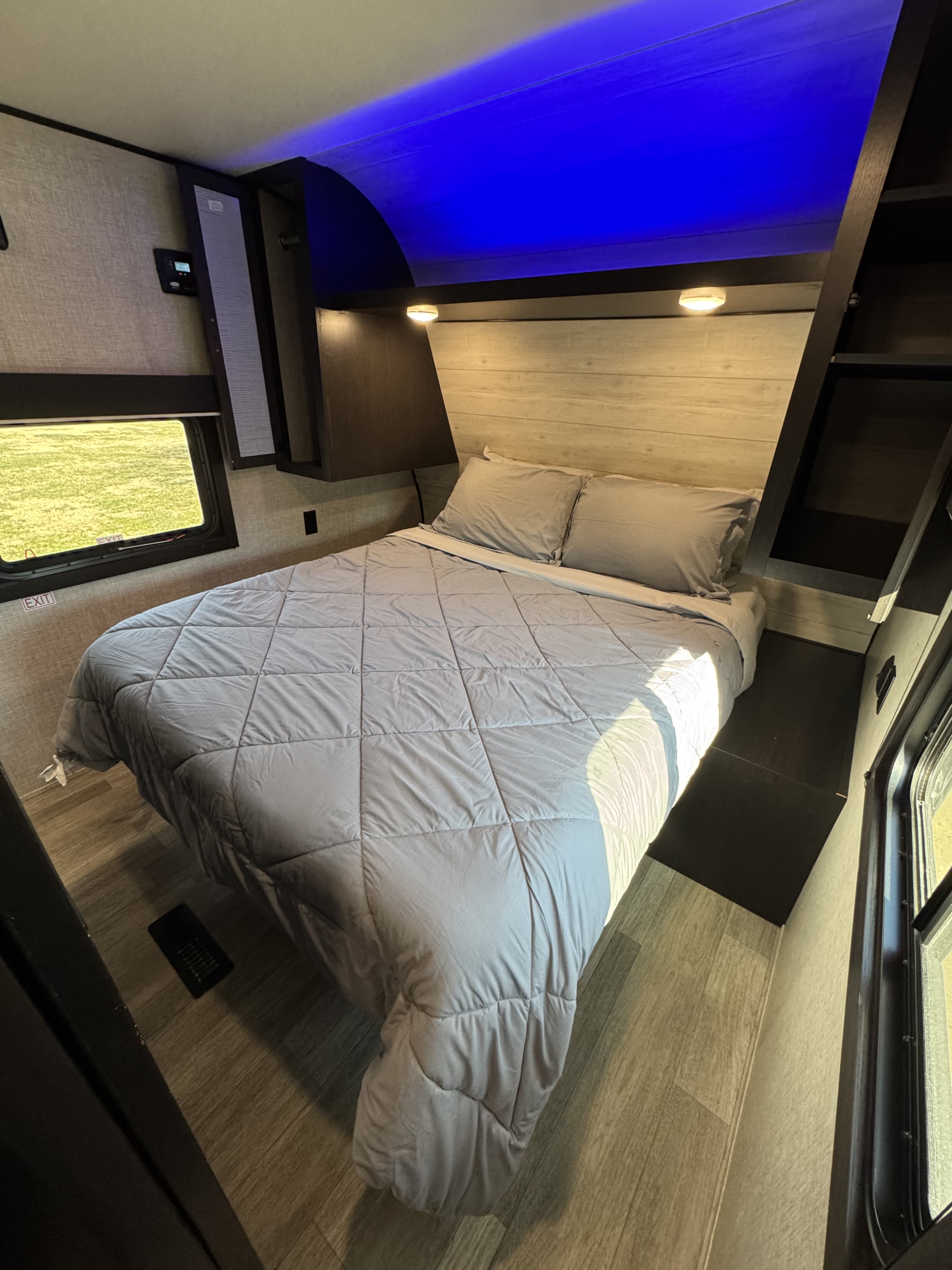 Cozy RV rental bedroom with a comfortable bed, modern blue lighting, built-in storage, and a view outside.. Jayco Jay Flight SLX 2022