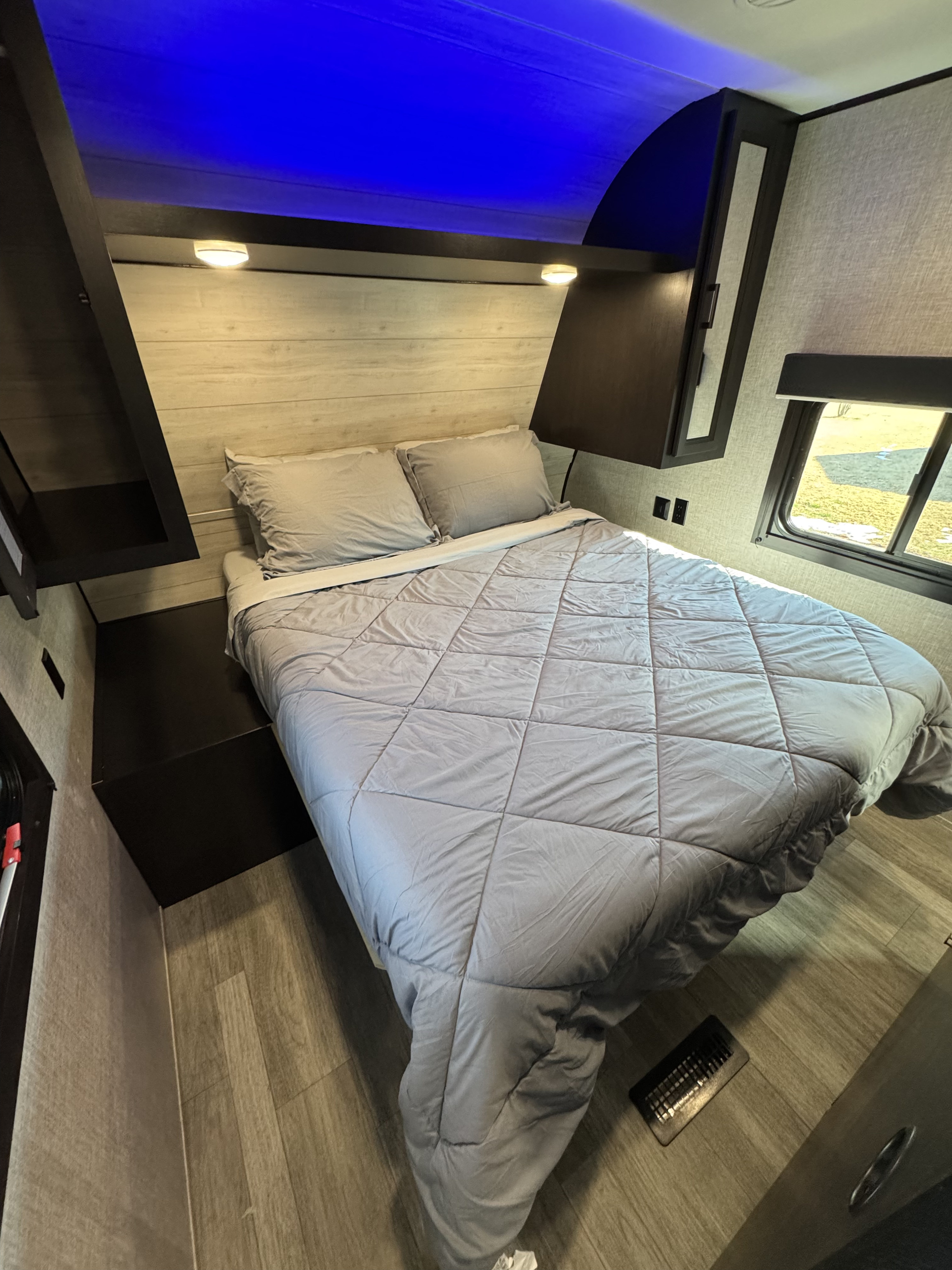 Relaxing RV rental bedroom with gray queen bed, blue accent lights, and wood-look floor.. Jayco Jay Flight SLX 2022