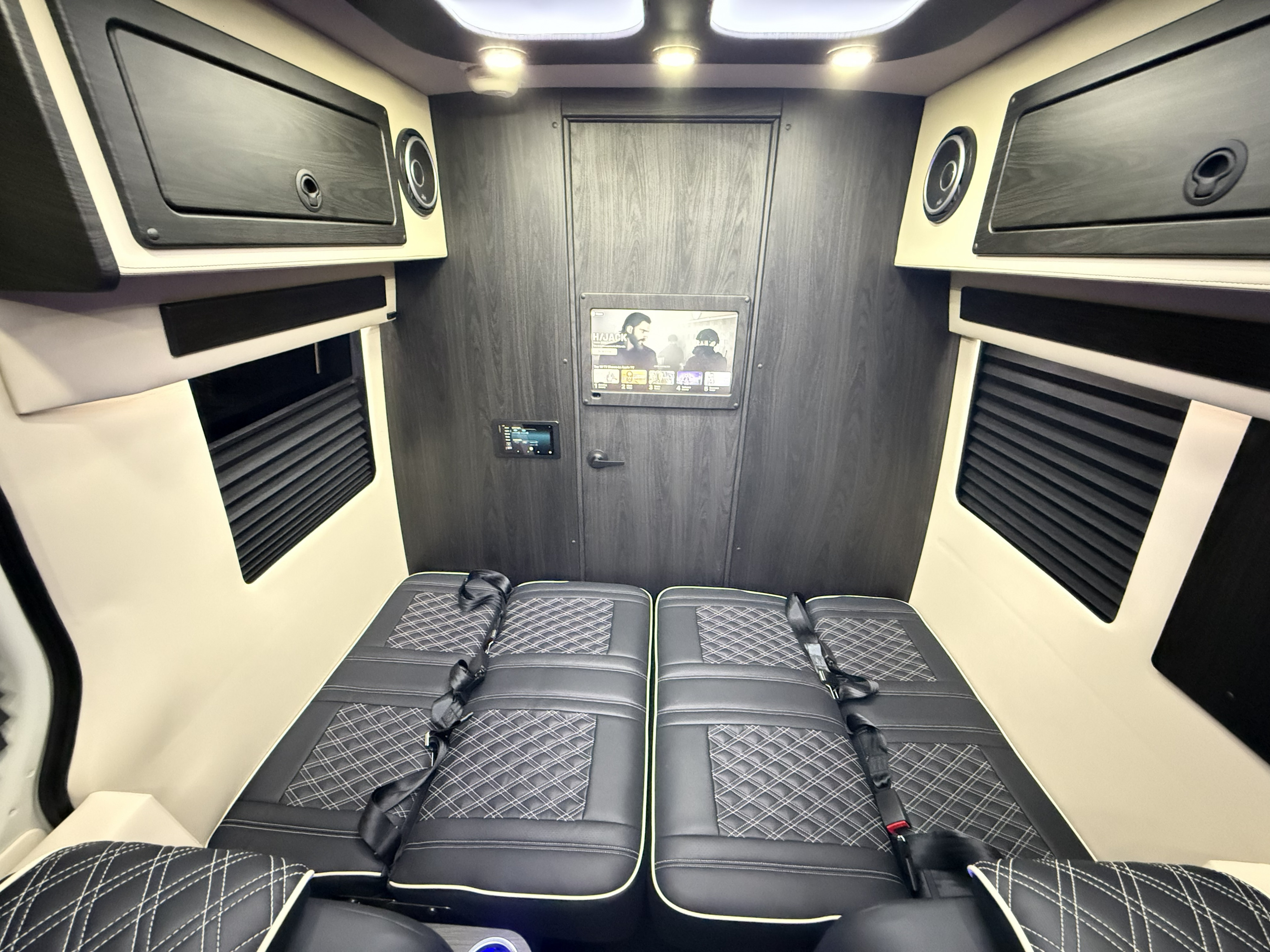 Stylish RV rental interior with black quilted seats, a mounted TV, storage, and modern paneling for comfortable travel.. OGV Luxury Coach V-Cruise 2026