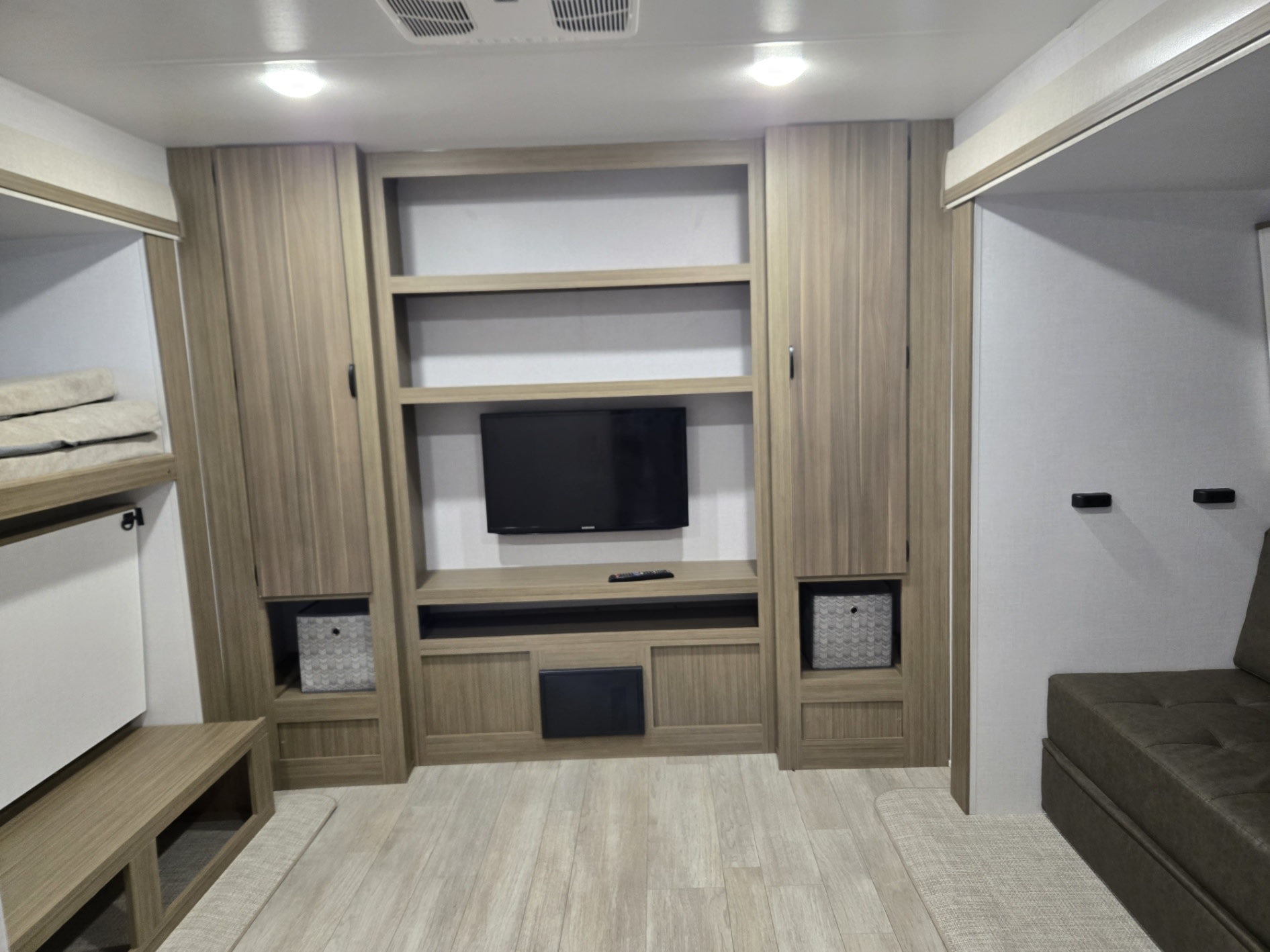 Modern RV rental interior featuring a TV, shelving, bunks, and a sofa. A functional and comfortable living space.. Wildwood 31KQBTS 2025