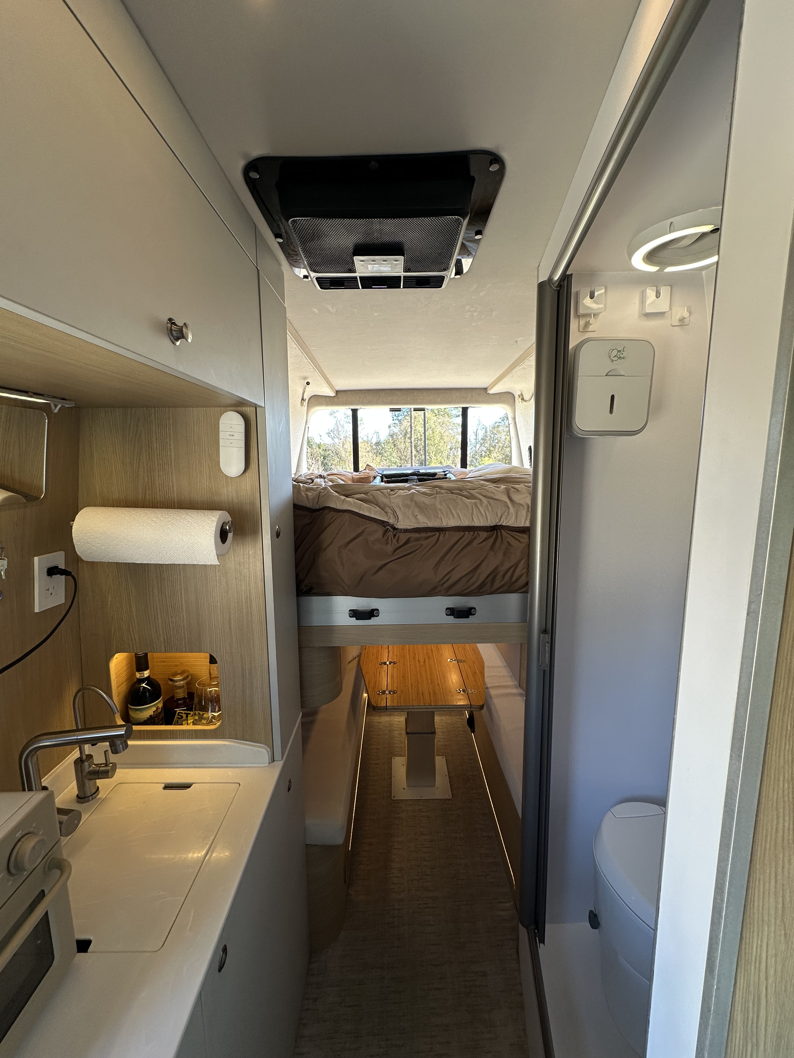 Explore this modern **rv rental** interior: a compact kitchen, elevated bed, and private shower/toilet area for travel.. Noovo Noovo Class B 2024