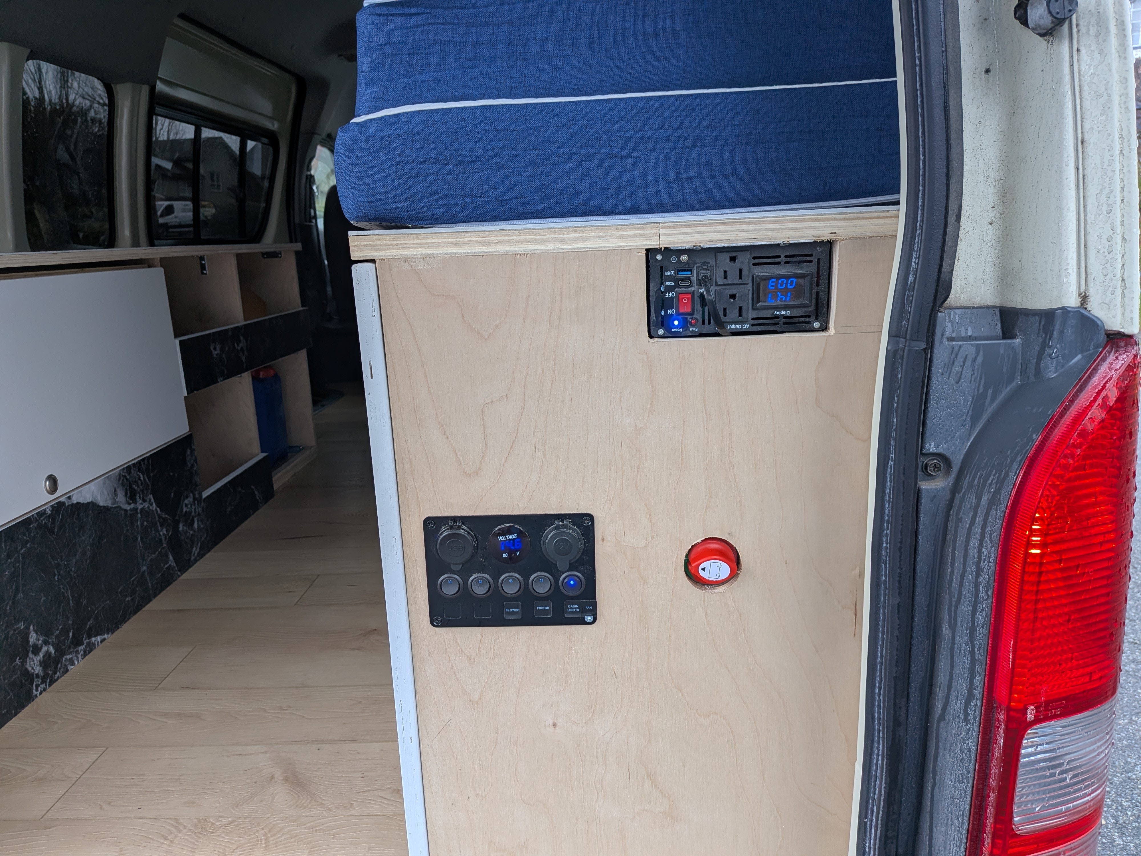 RV rental camper interior with a custom electrical system: power inverter, control panel (14.1V, USB, switches), and bed.. Toyota Hiace 2006