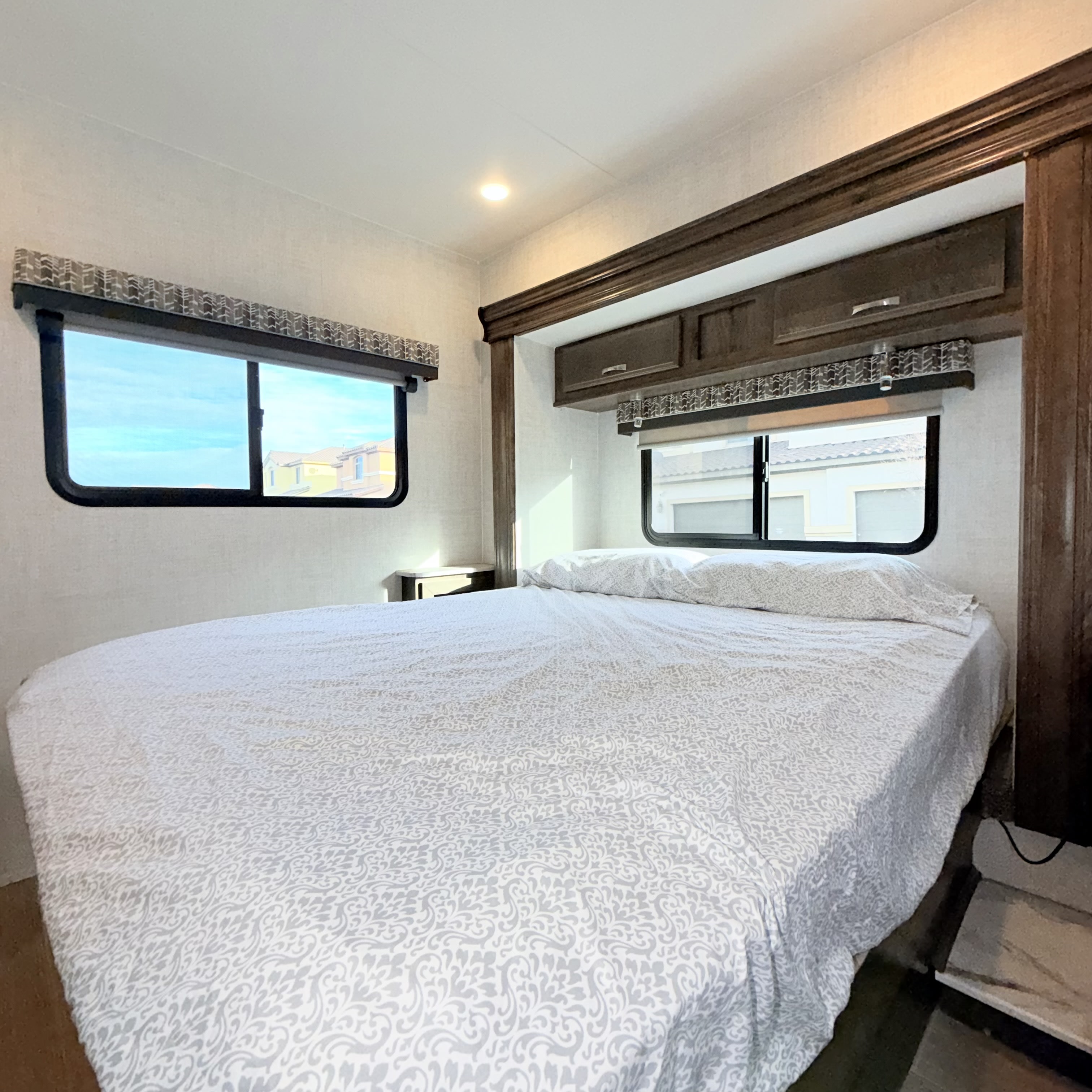 Comfortable RV rental bedroom with modern decor, a large bed, and compact storage, perfect for travel accommodations.. Gulf Stream Conquest 2021