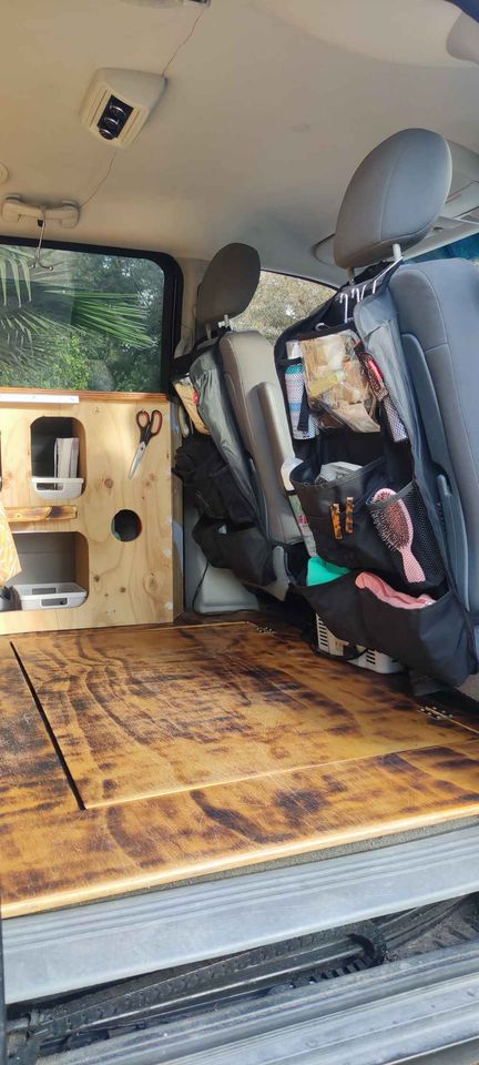 Practical RV rental van interior with custom wooden floor, built-in storage on left, and seatback organizers on right.. Dodge Grand Caravan 2009