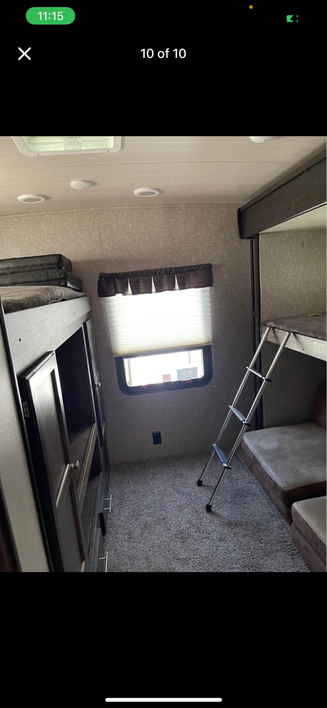 RV rental bunkhouse interior with upper & lower bunk beds, a ladder, window, and cabinets. Carpeted floor shown.. Heartland RVs Mallard 2020