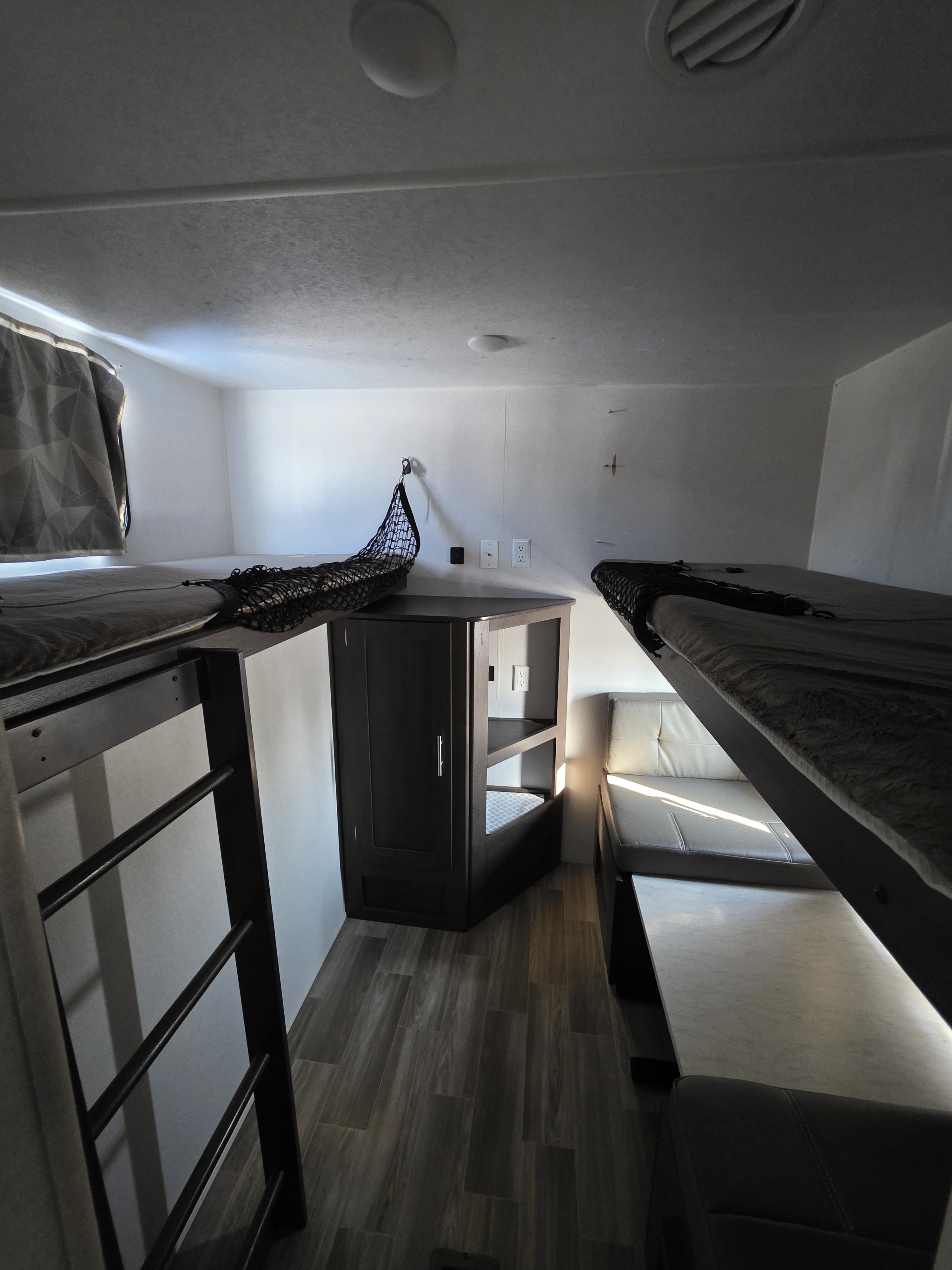 Cozy RV rental interior with bunk beds, ladder, storage cabinet, and dinette seating, featuring wood-look flooring.. Forest River Salem 2019