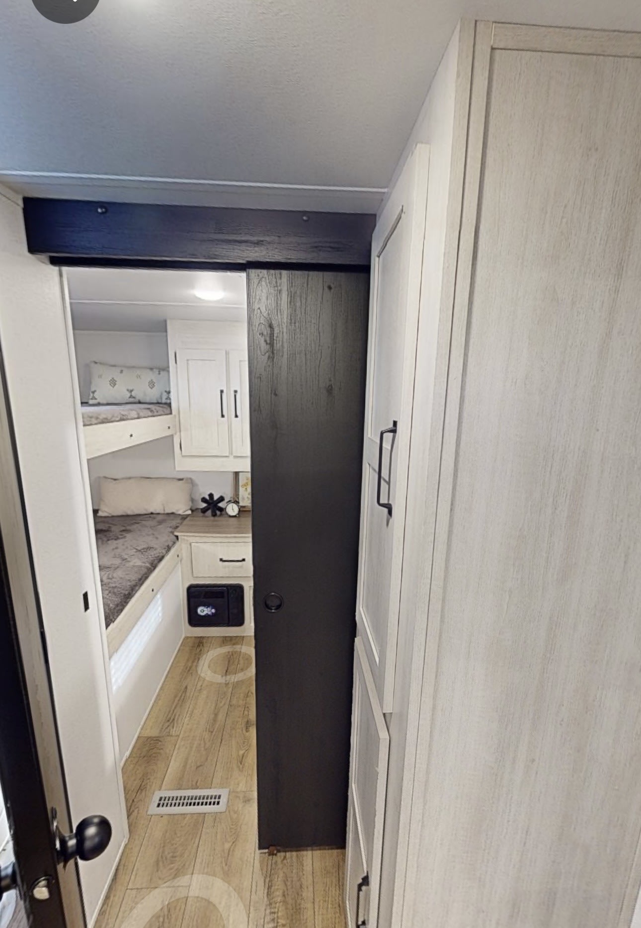 An RV rental's cozy bunkhouse area, featuring bunk beds, a dark sliding door, and light wood storage cabinets.. Forest River Palomino Puma Camping Edition 2025
