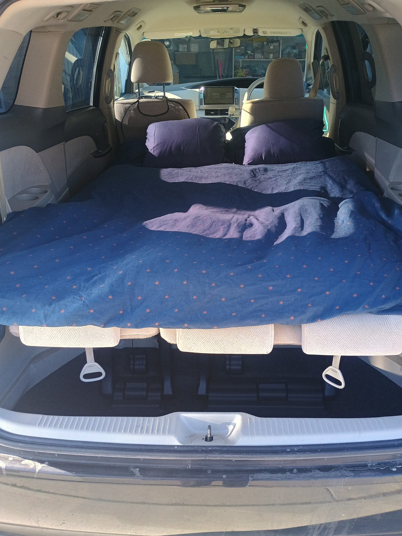 Car camping setup, perfect for an affordable RV rental alternative. Minivan's rear converted into a cozy bed with pillows & blanket.. Toyota HIACE CAMPERVAN 2009