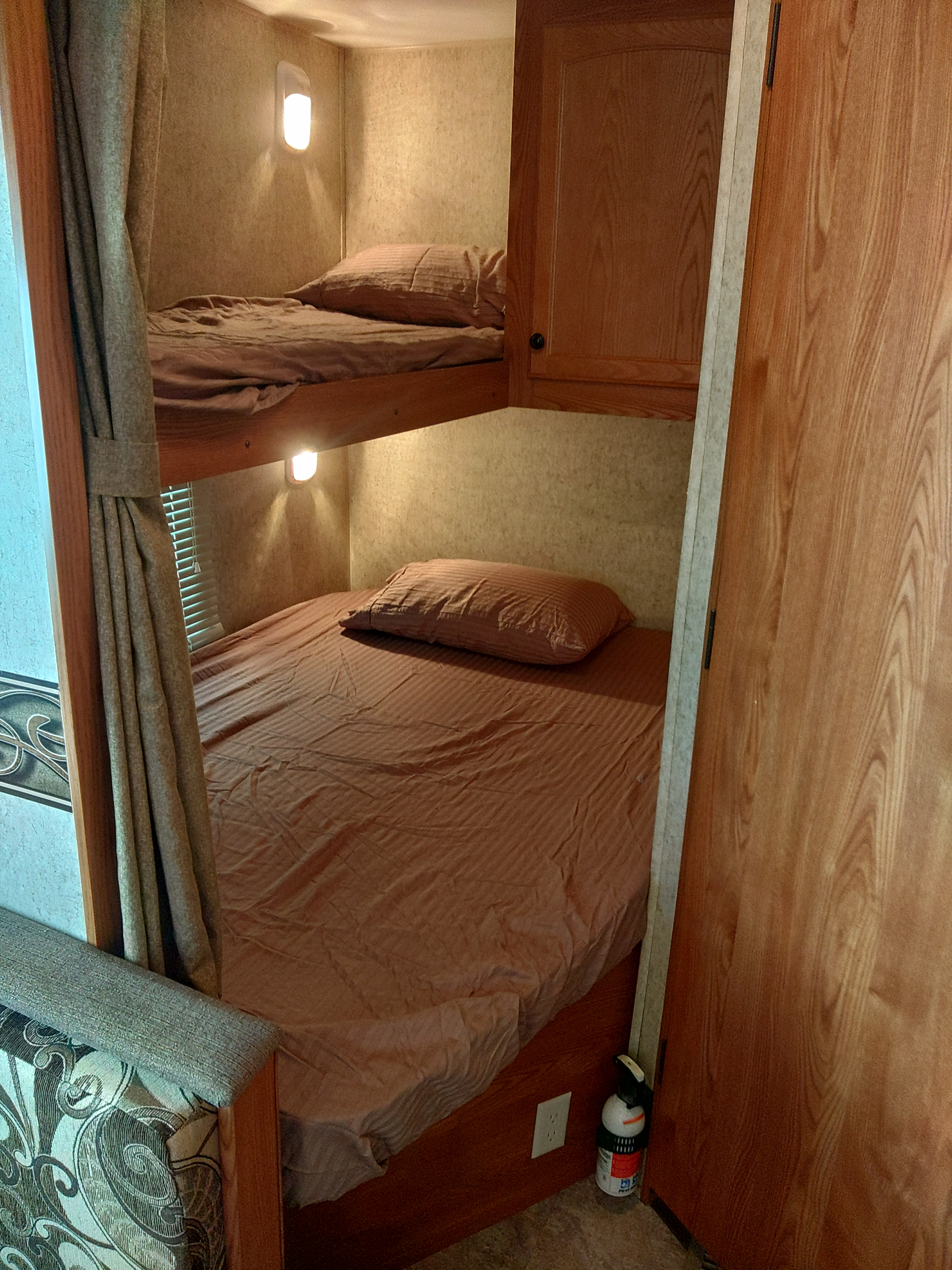 Cozy rv rental bunk beds featuring brown bedding, individual reading lights, and wooden cabinetry in a compact space.. Heartland RVs Trail Runner 2012