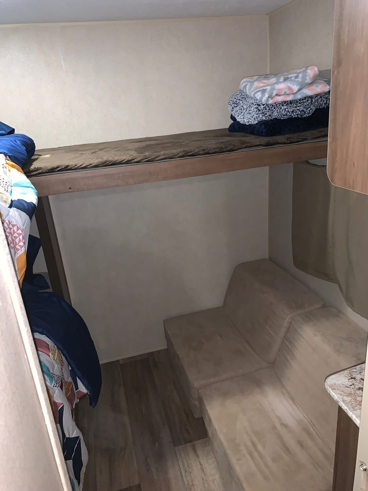RV rental interior shows bunk beds with folded blankets & lower couch seating. Ideal for compact living and travel.. Aspen Trail Aspen Trail Trailer 2018