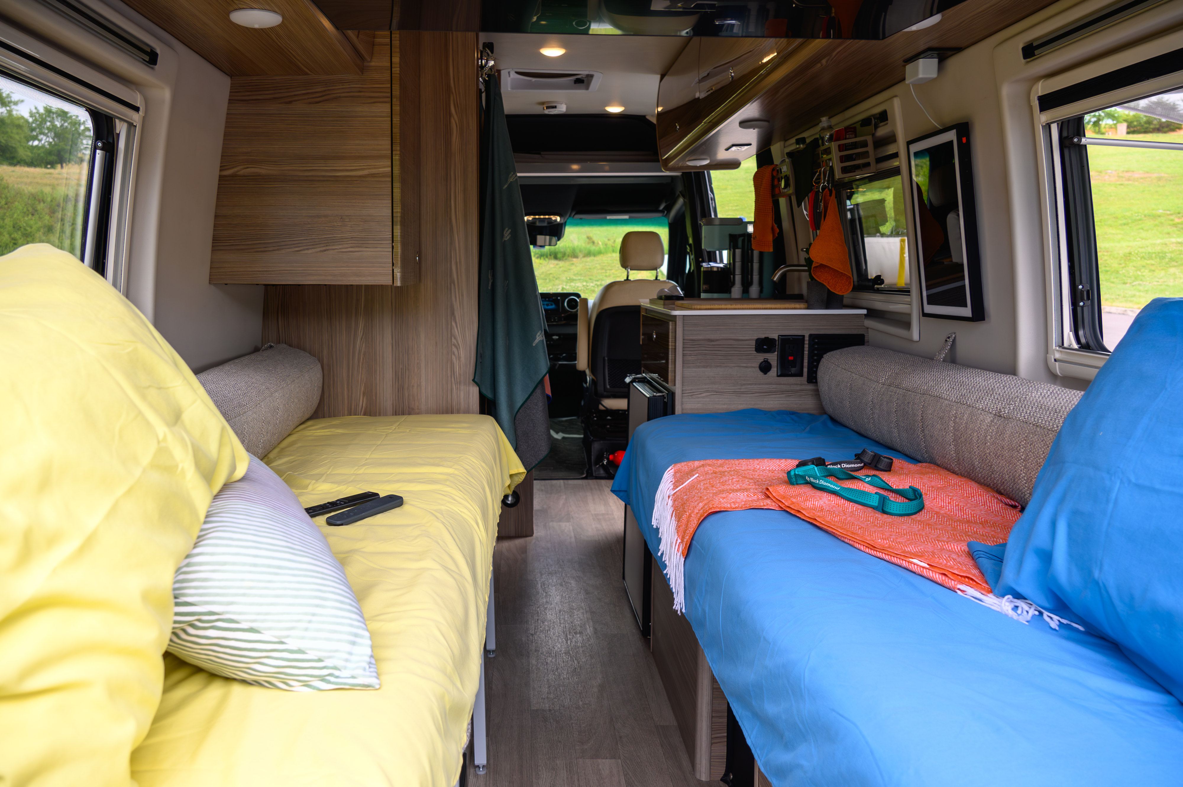 Cozy rv rental interior with twin beds, bright bedding, and compact kitchen. Ideal for a comfortable road trip.. Winnebago Boldt 2022