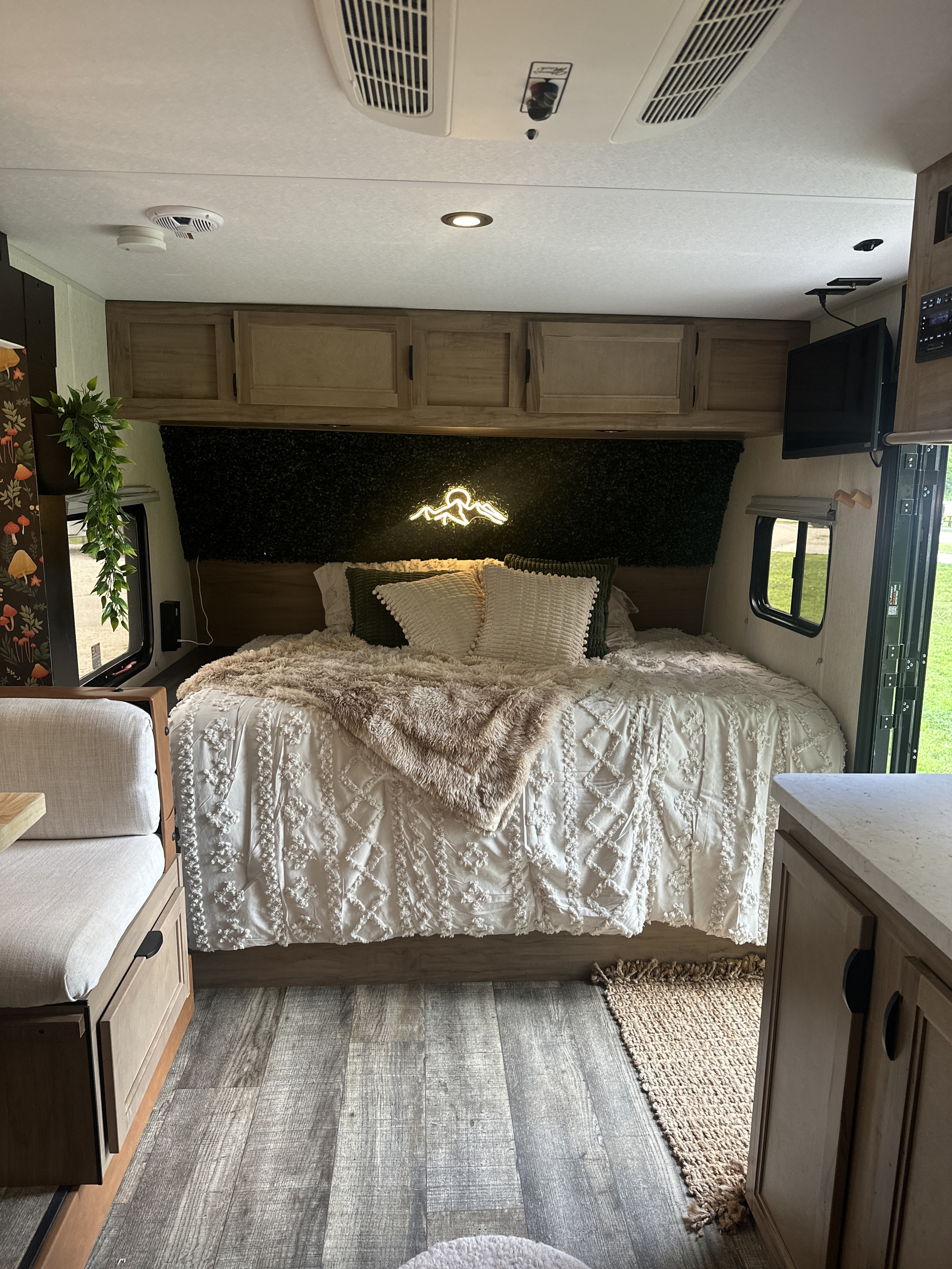 Cozy RV rental bedroom featuring a large bed with fluffy bedding, stylish decor, ample storage, and warm lighting.. Forest River Cherokee Wolf Pup 2024